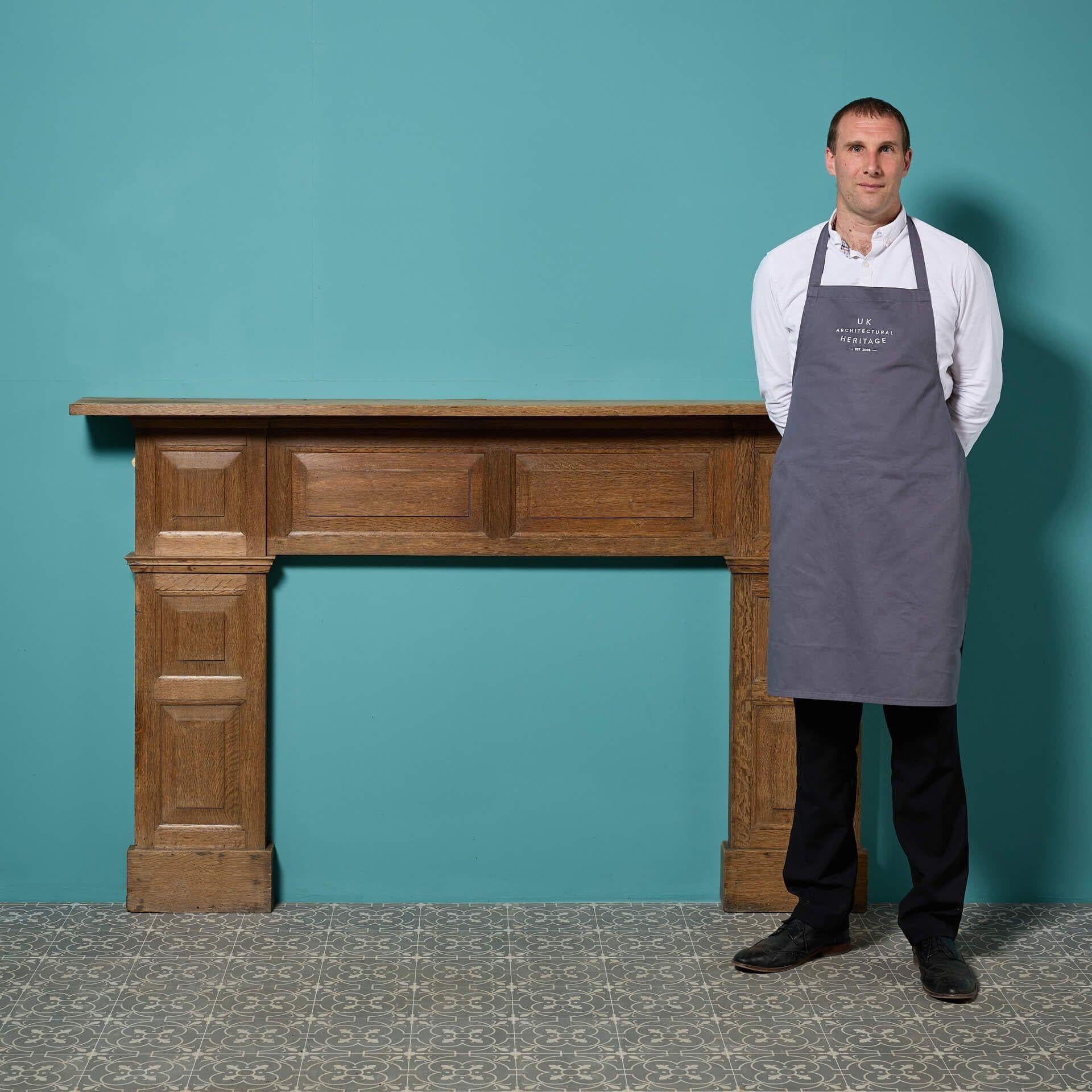 Un grande camino in legno di Oak del XIX secolo in stile georgiano. Semplicemente decorato con pannelli in rilievo e a campi, questo antico caminetto in legno è un'aggiunta senza tempo alle proprietà vecchie e nuove. La finitura cerata mette in