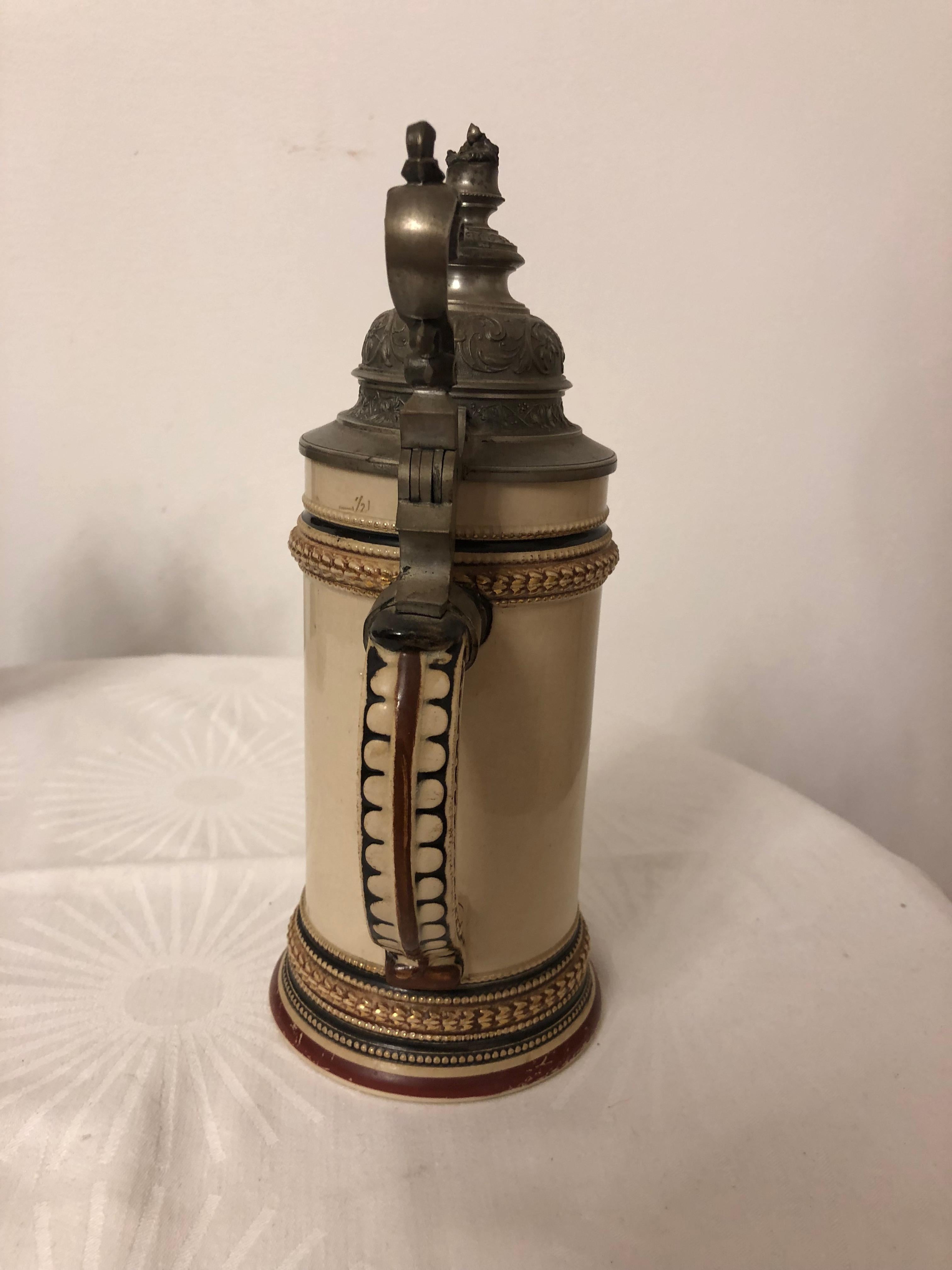 Stoneware 1/2 liter beer stein with an original pewter hinged lid. The body is decorated with a tavern scene.
Made in Germany, circa 1880. Some repairs.