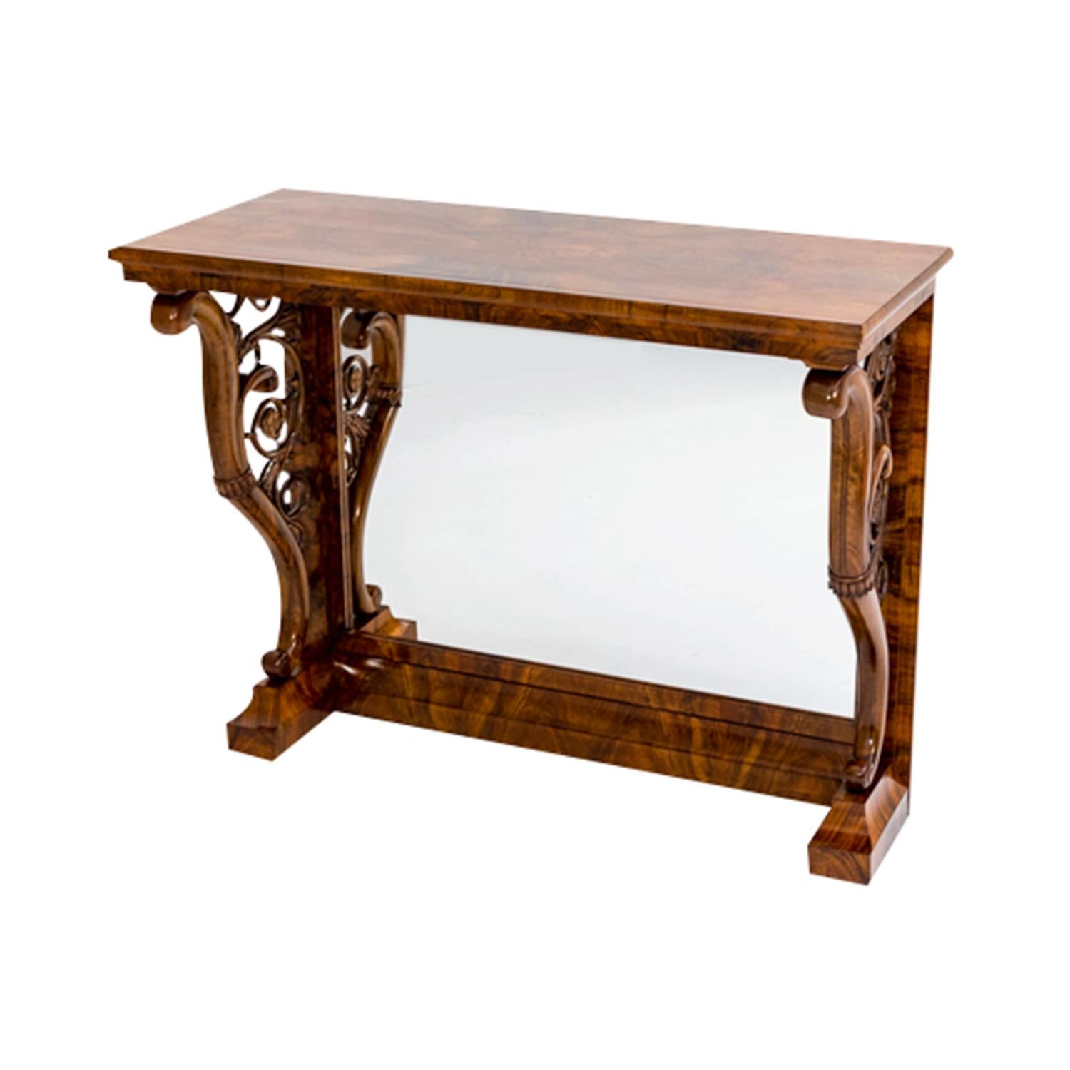 A light-brown, antique German Biedermeier freestanding wall console table made of hand crafted shellac polished Walnut, in good condition. The tall table is composed with the original mirrored back panel and openwork side panels with vine motifs,