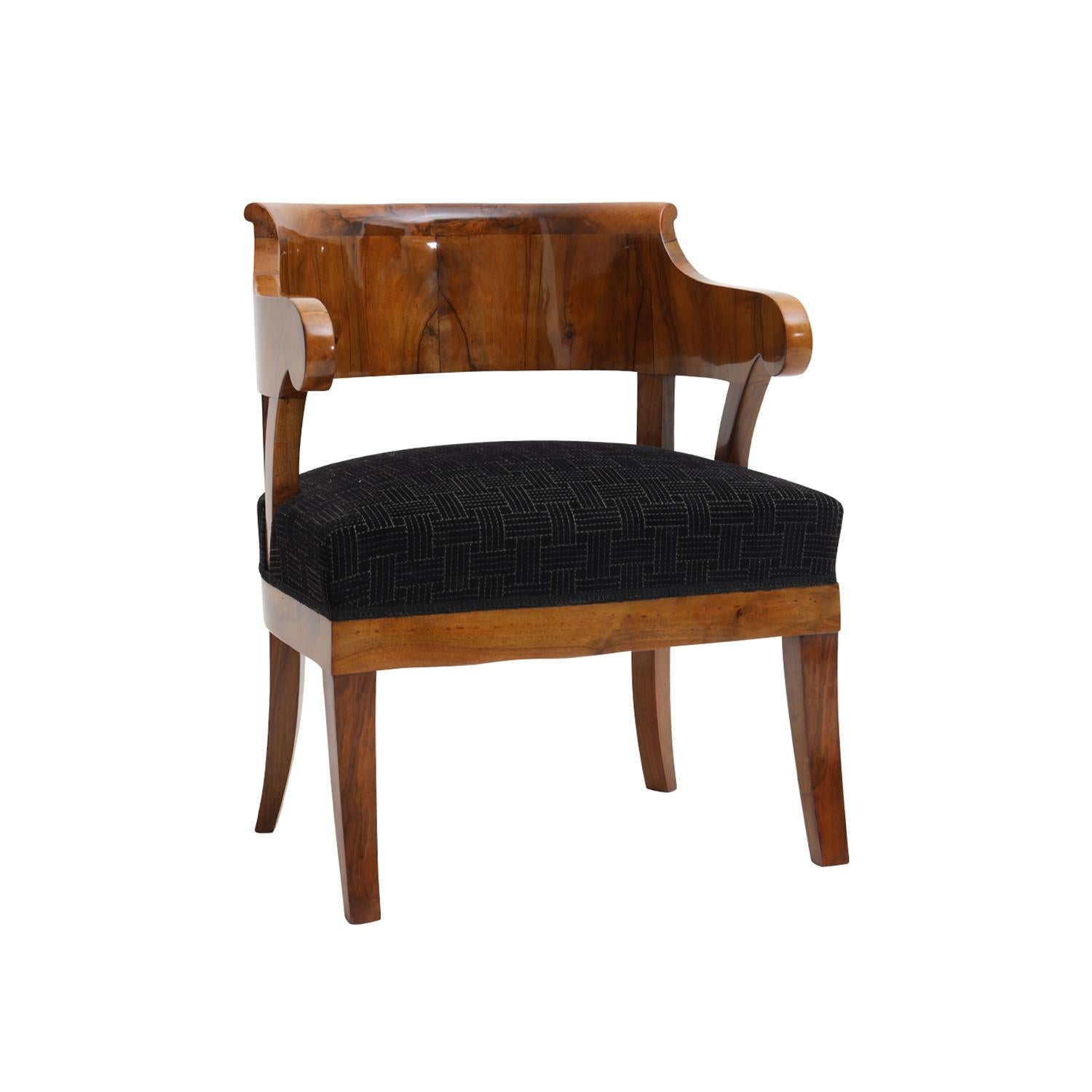 A light-brown, antique German Biedermeier single armchair made of hand crafted shellac polished, partly veneered Mahogany in very good condition. The side, end chair has an arched, curved backrest standing on four wooden legs. Newly upholstered in a