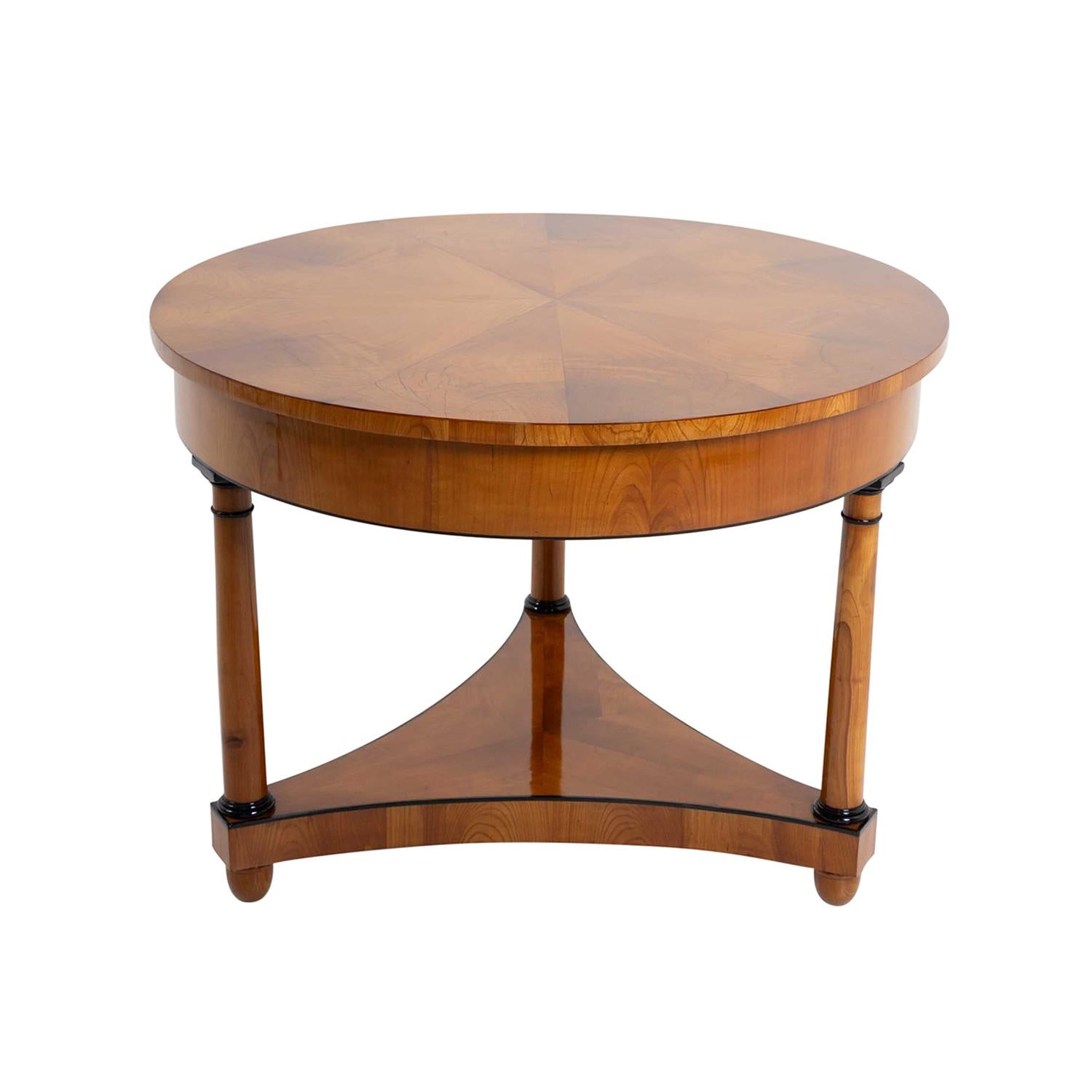 Ein runder, antiker deutscher Biedermeier-Mitteltisch aus handgefertigtem, schellackpoliertem, teilweise furniertem Nussbaum, in gutem Zustand. Der kleine Serviertisch besteht aus einer breiten Schürze, die auf drei runden Beinen steht, die durch