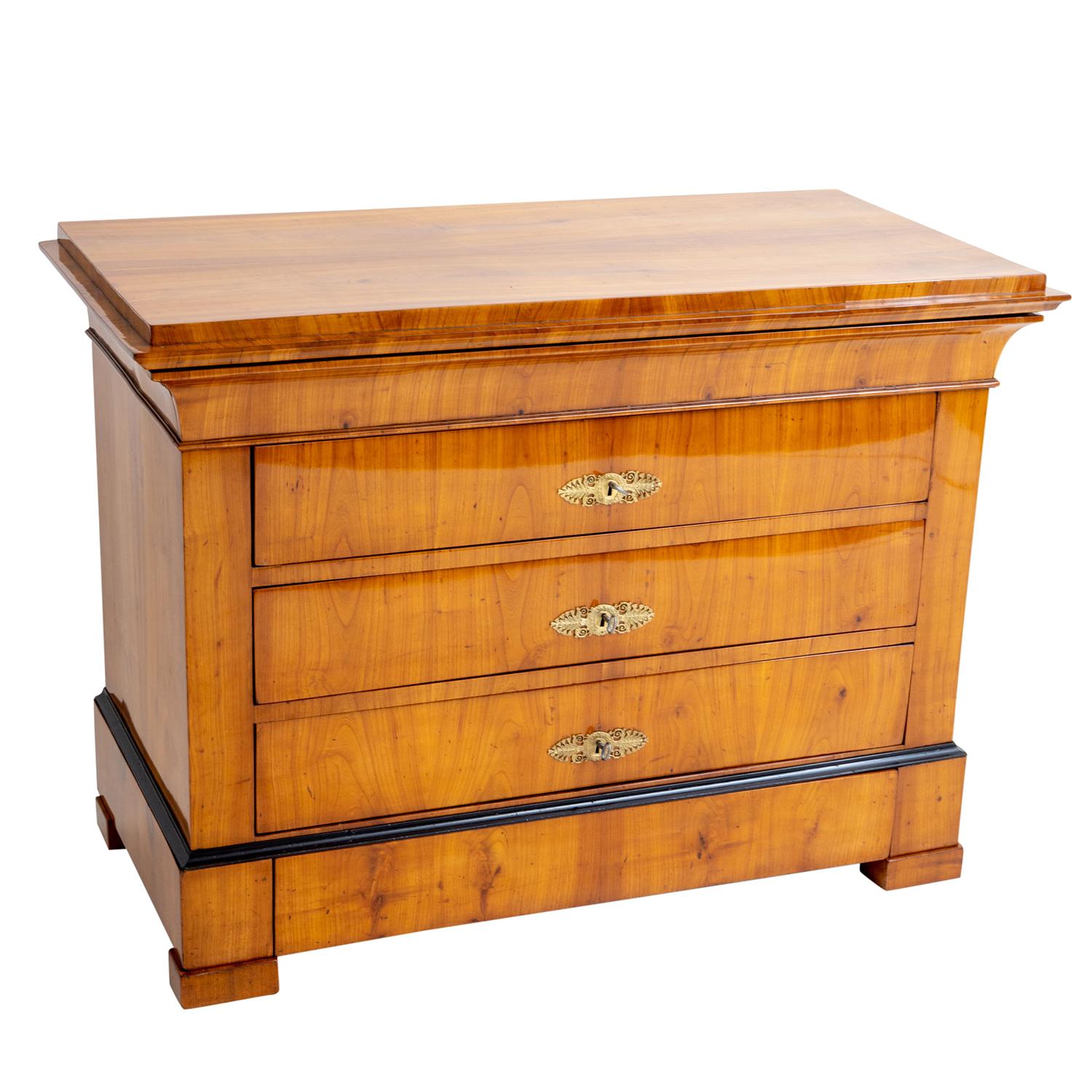 An antique German Biedermeier single chest made of hand crafted shellac polished, partly veneered Cherrywood, in good condition. The detailed cabinet is composed with five drawers, consisting its original hardware and keys, enhanced by polished