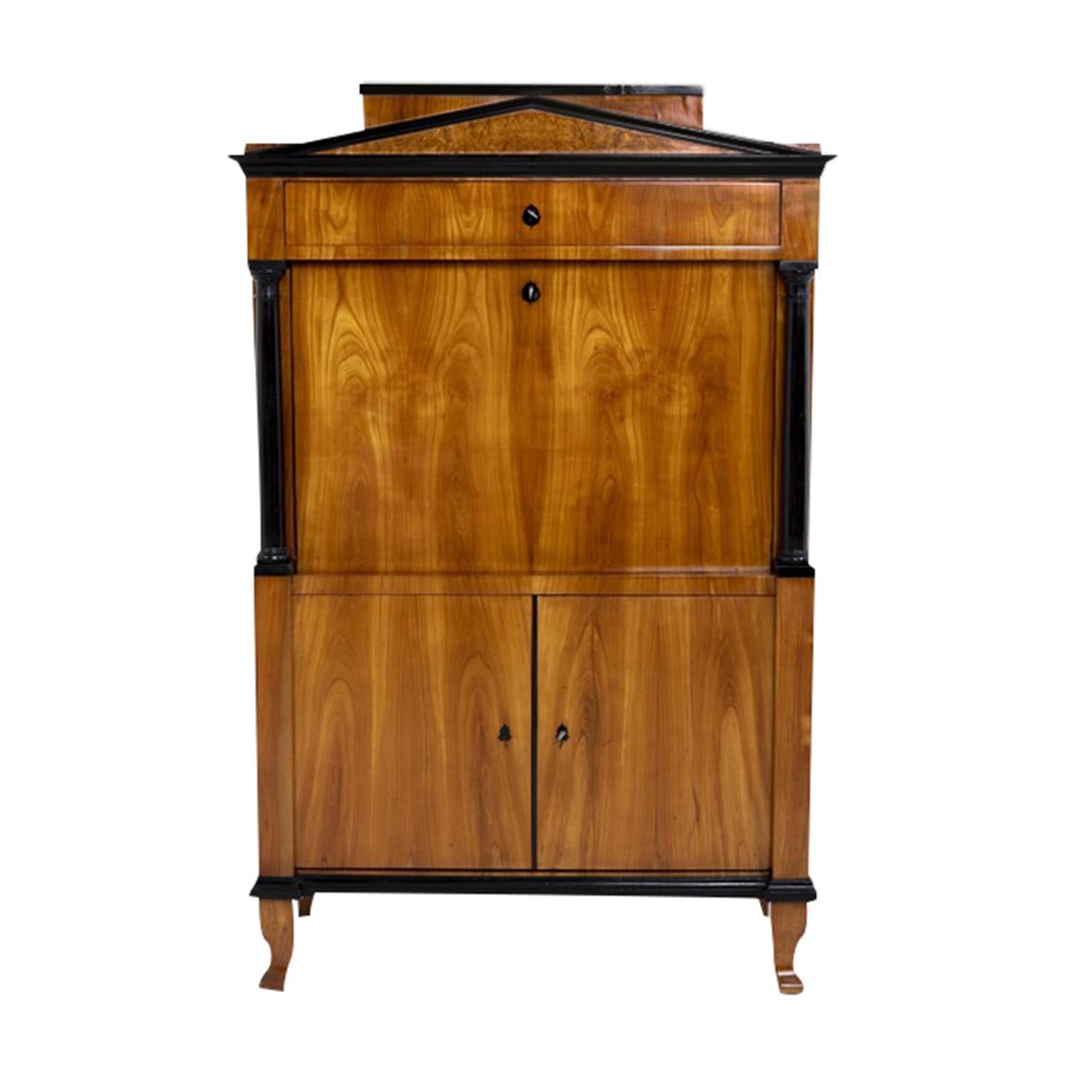 A 19th Century, antique German Biedermeier tall secretaire with a writing flap made of hand crafted shellac polished, partly veneered Cherrywood and Burlwood, in good condition. The bottom part of the detailed secretary is composed with two doors