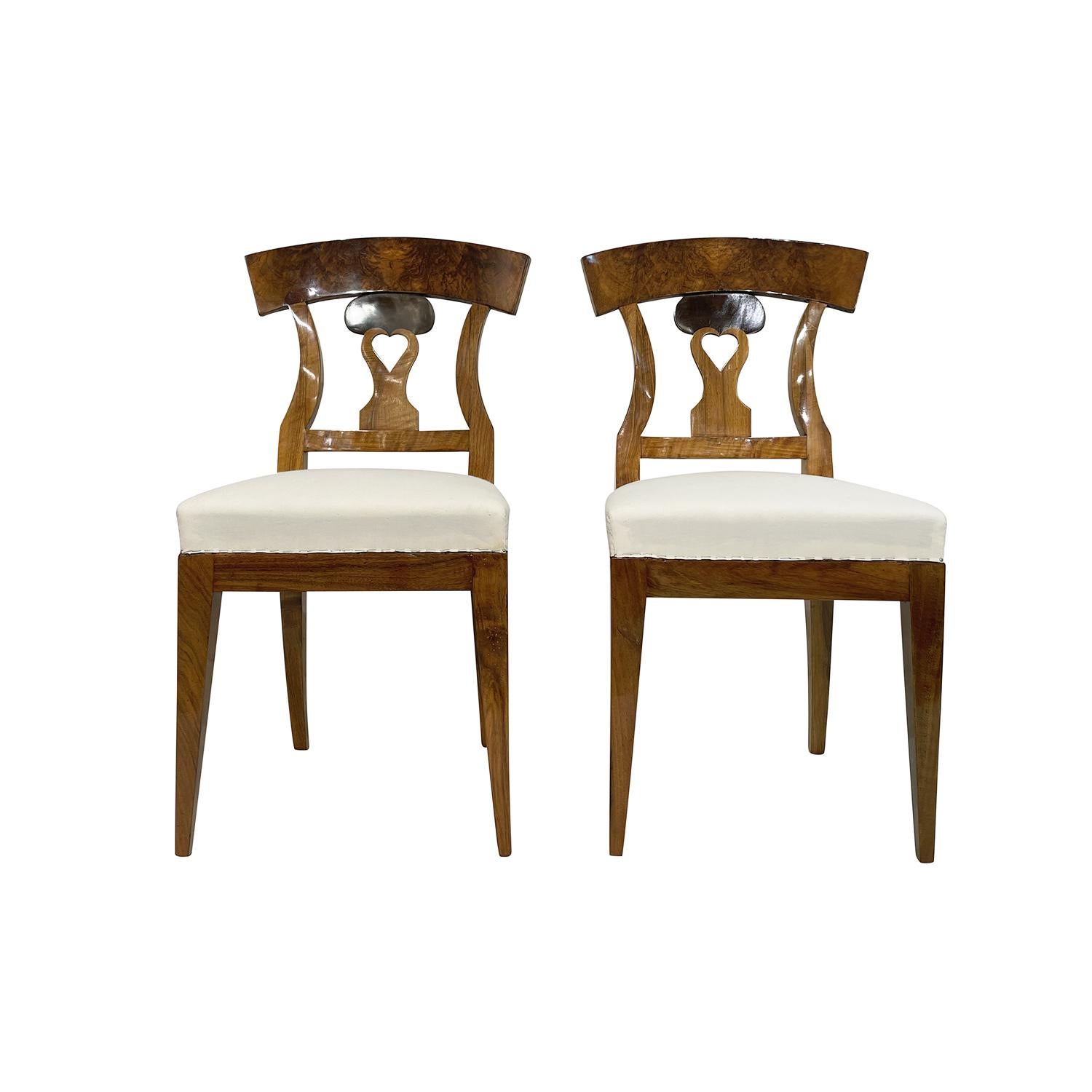 A light-brown, antique German Biedermeier set of four dining room chairs made of hand crafted shellac polished, partly veneered Cherrywood, in very good condition. The detailed side chairs have an open arched and curved backrests, standing on four