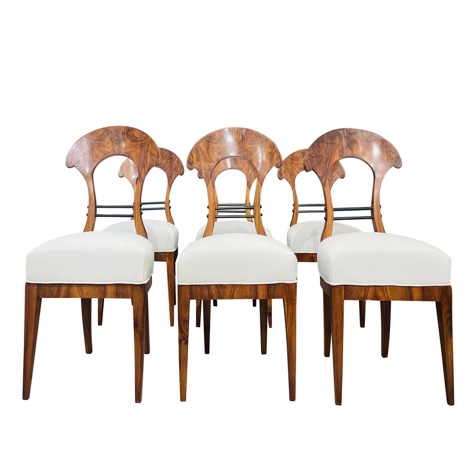 An early 19th Century, antique German Biedermeier set of six dining room chairs made of hand crafted polished, partly veneered Walnut, in good condition. The side chairs have an open, detailed carved shield backrest, particularized on the bottom by