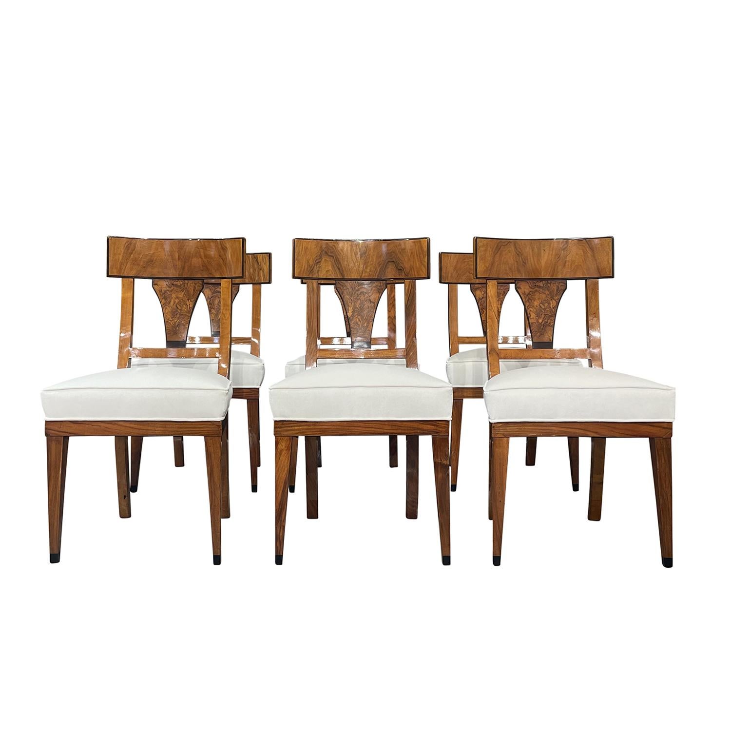 An antique German Biedermeier set of six dining room chairs made of hand crafted polished, partly veneered Walnut, in good condition. The side chairs have an open, detailed carved backrest, standing on four tapered straight wooden legs. The backrest