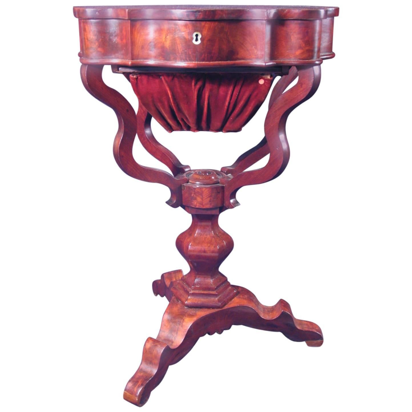 Original 19th century Biedermeier sewing table, mahogany veneer. This unique exquisite table comes from Northern Germany. 
The locking, hinged lid raises to reveal nine compartments, the lid of the central compartment is beautifully decorated with