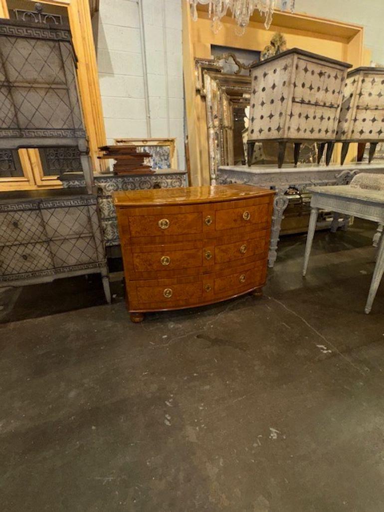This 19th Century German Biedermeier Shaped Front Burl Walnut Commode features a modern style with antique origins. Featuring a gorgeous wood finish and clean lines. Its burl walnut construction gives it a unique and elegant appearance, making it a