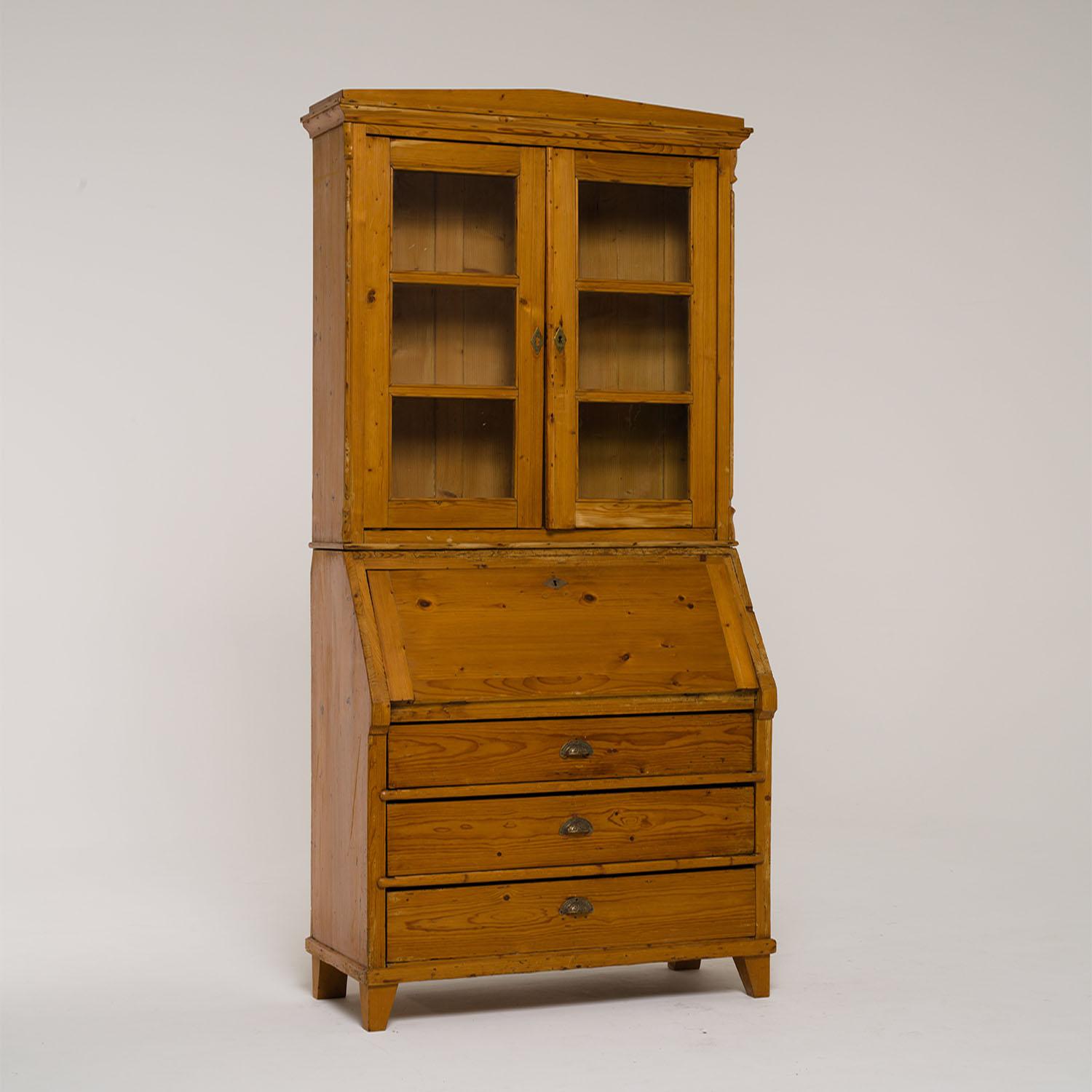 An antique German Biedermeier two part bureau, secretary with a two door glass display made of hand crafted Pinewood, in good condition. The upper part of the secretaire is composed with a transom-glazed attachment with a small pointed gable, the