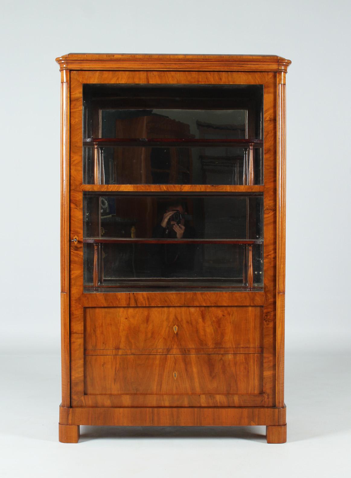 Dimensions: H x W x D: 155 x 93 x 45 cm. Depth of the shelves: 35 cm.

Beautiful antique display cabinet from the Biedermeier period around 1835.
The front of the piece of furniture is divided into two mock drawers in the lower part and two