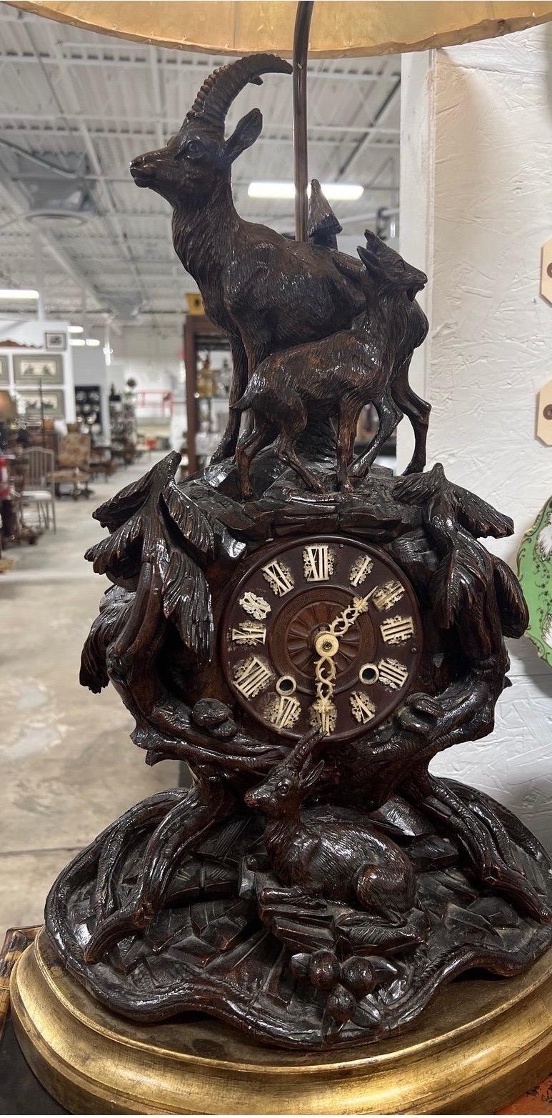 An exceptional large scale 19th century black forest mantle clock with fine carved mountain goats and tree forms to the body - resting on a gilt wood base and wired for a lamp! Includes cowhide shade.
Note: clock is now quartz movement.