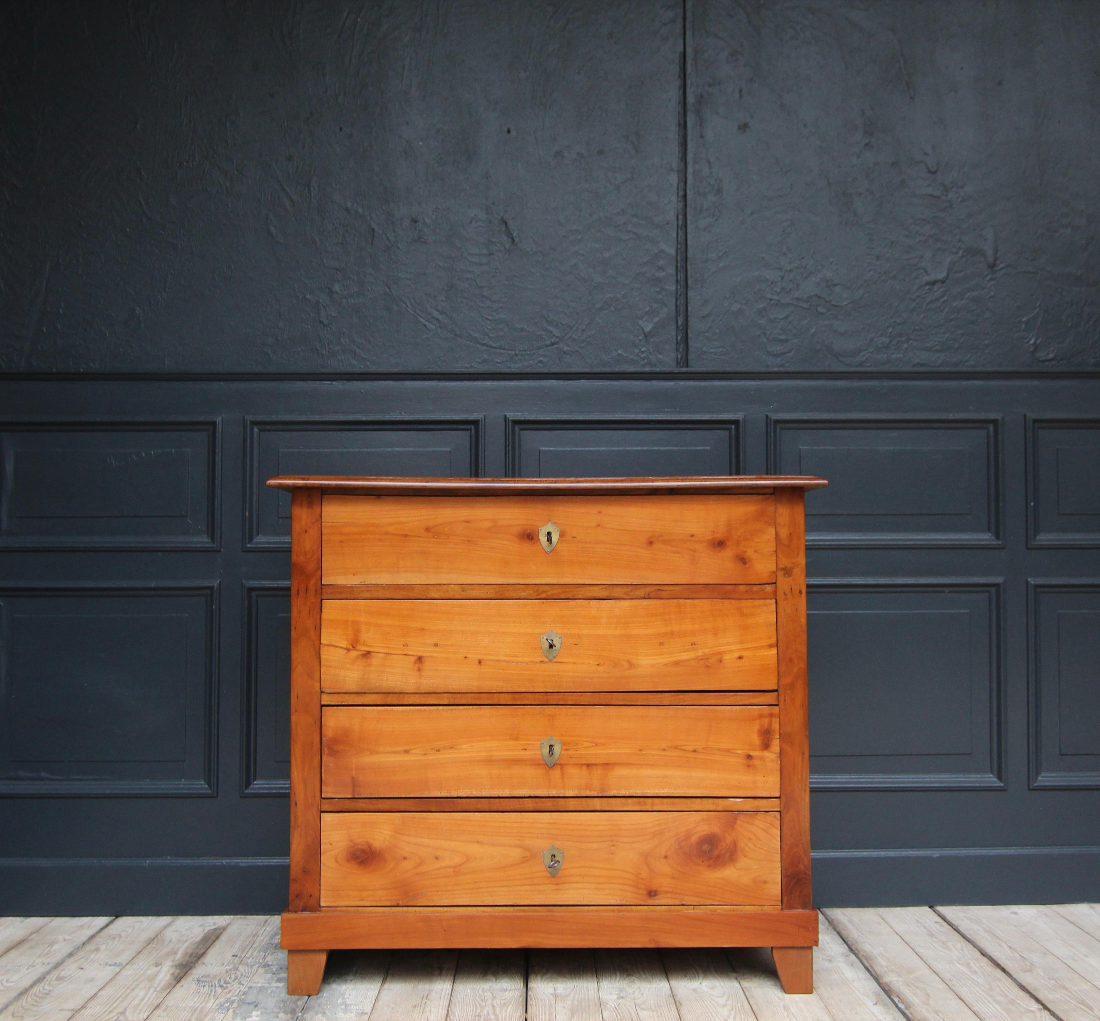 A German late-biedermeier cherrywood chest of drawers from the 2nd half of the 19th century. 

Plain cherrywood body with coffered sides, 4 drawers and slightly protruding moulded top panel.

Original locks.

Brass key plates in the shape of coats