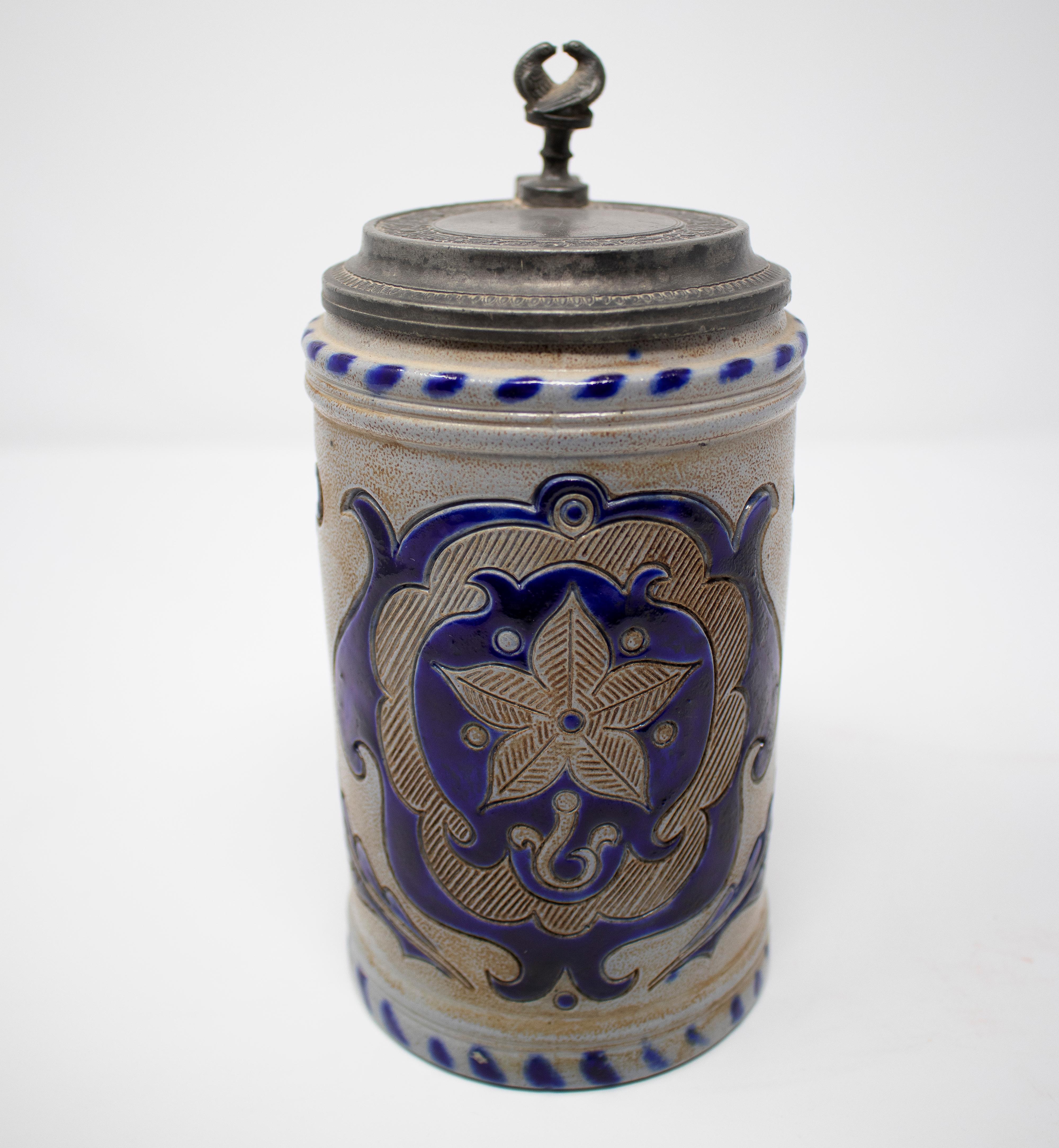 19th century German earthenware beer stein mug with tin lid and cobalt blue ornamental decoration.
  