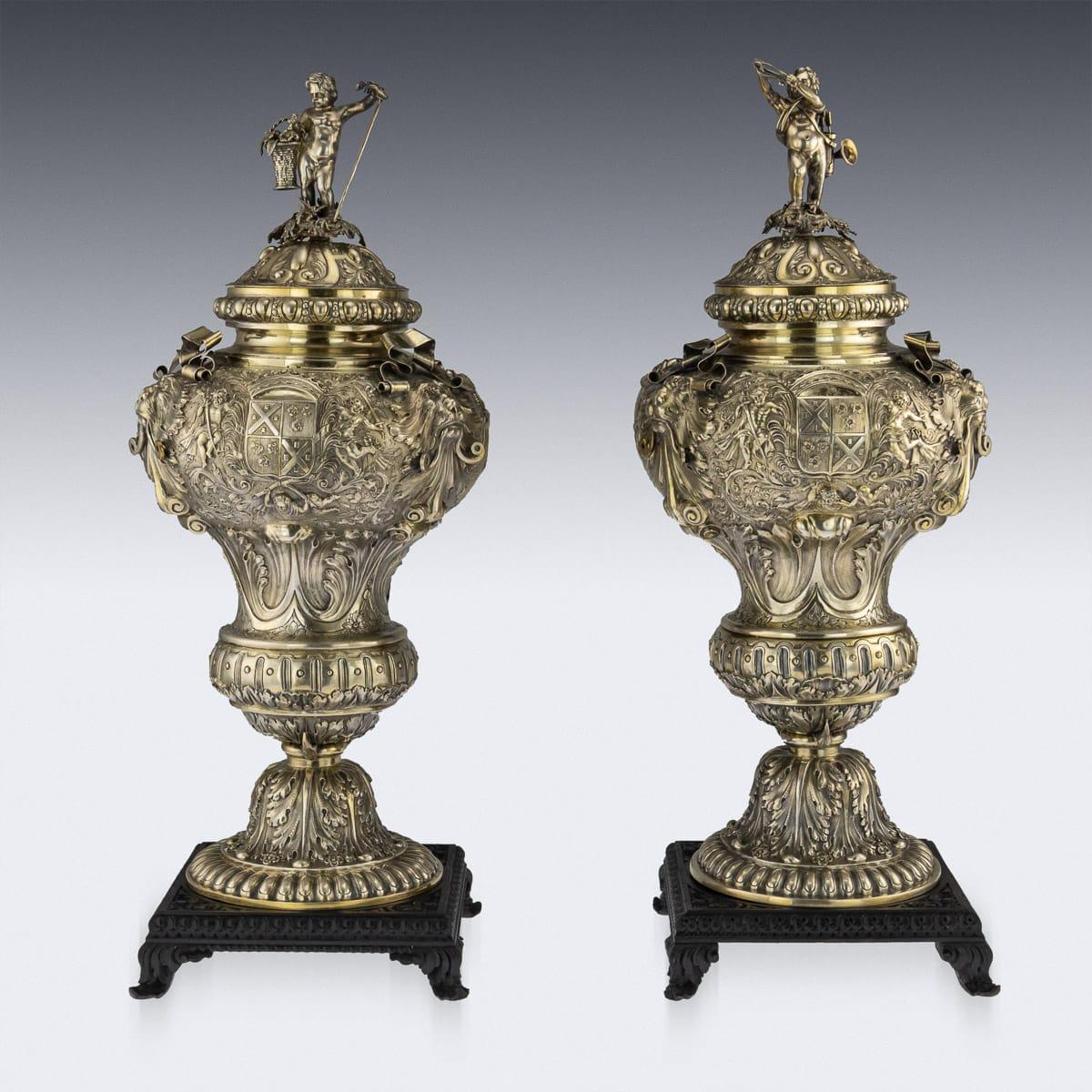Antique 19th century German (Hanau) magnificent solid silver-gilt pair of large lidded vases. Of inverted pear shape on acanthus leaf and lobed bases, both chased with elaborate coats-of-arms flanked by putti with swords and two agricultural scenes,