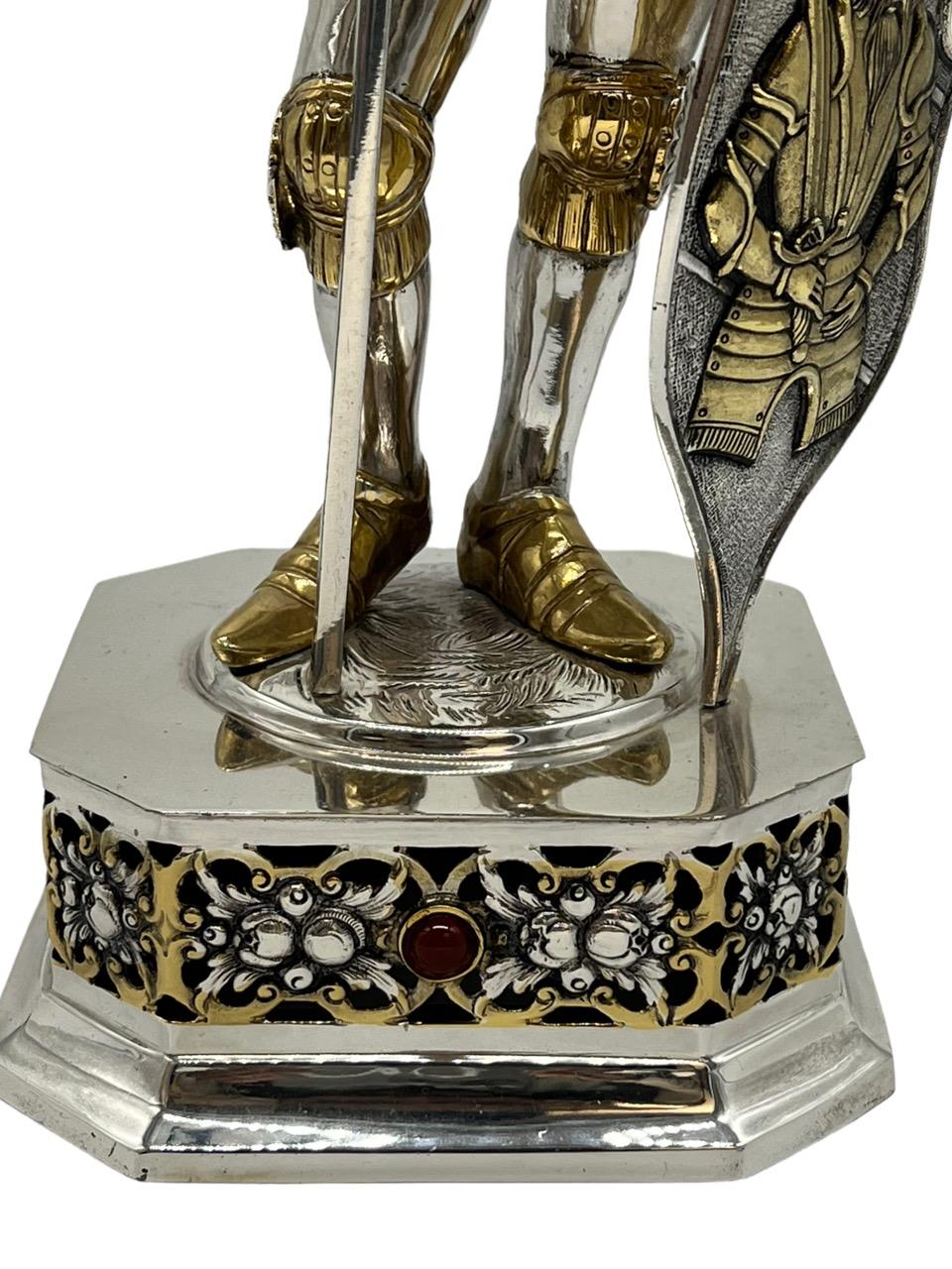 19th Century German extremely detailed sterling silver and gold gilt knight figure. Knight in full suit of armour, carved face beneath a hinged visor made of white bone. The knight is holding an axe and a a shield, chased with armorials. It is