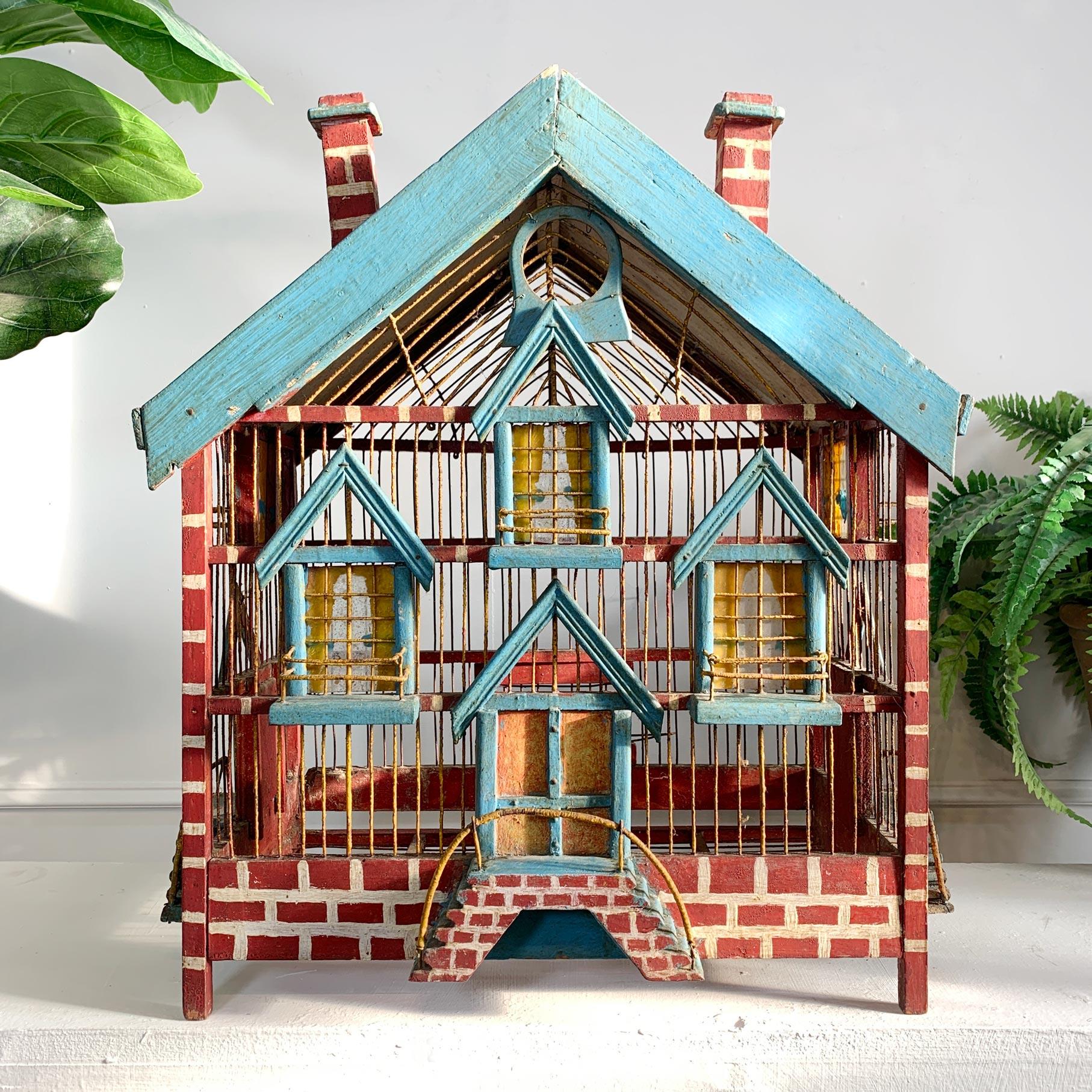 A charming late 19th century hand crafted primitive folk art bird cage, in the manner of a chateau, painstakingly detailed with hand painted red  brickwork, steps, painted glass windows and balconies. The vaulted roof with painted tiles and blue
