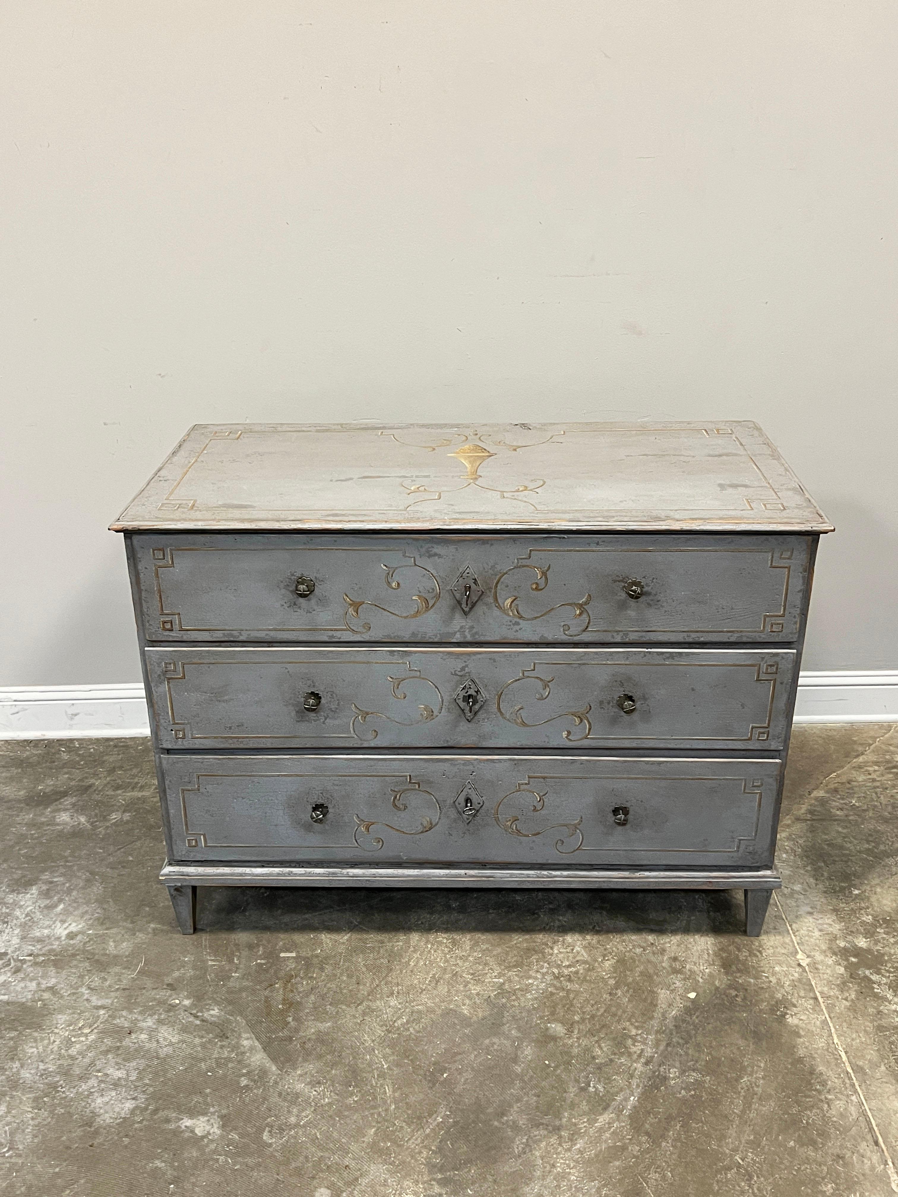 Generous sized mid 19th century chest of drawers beautifully painted in a soft blue-gray accented with delicate neo-classic design overpainted on the three drawers, sides and top. The base of the chest is straight and finished with molding and rests