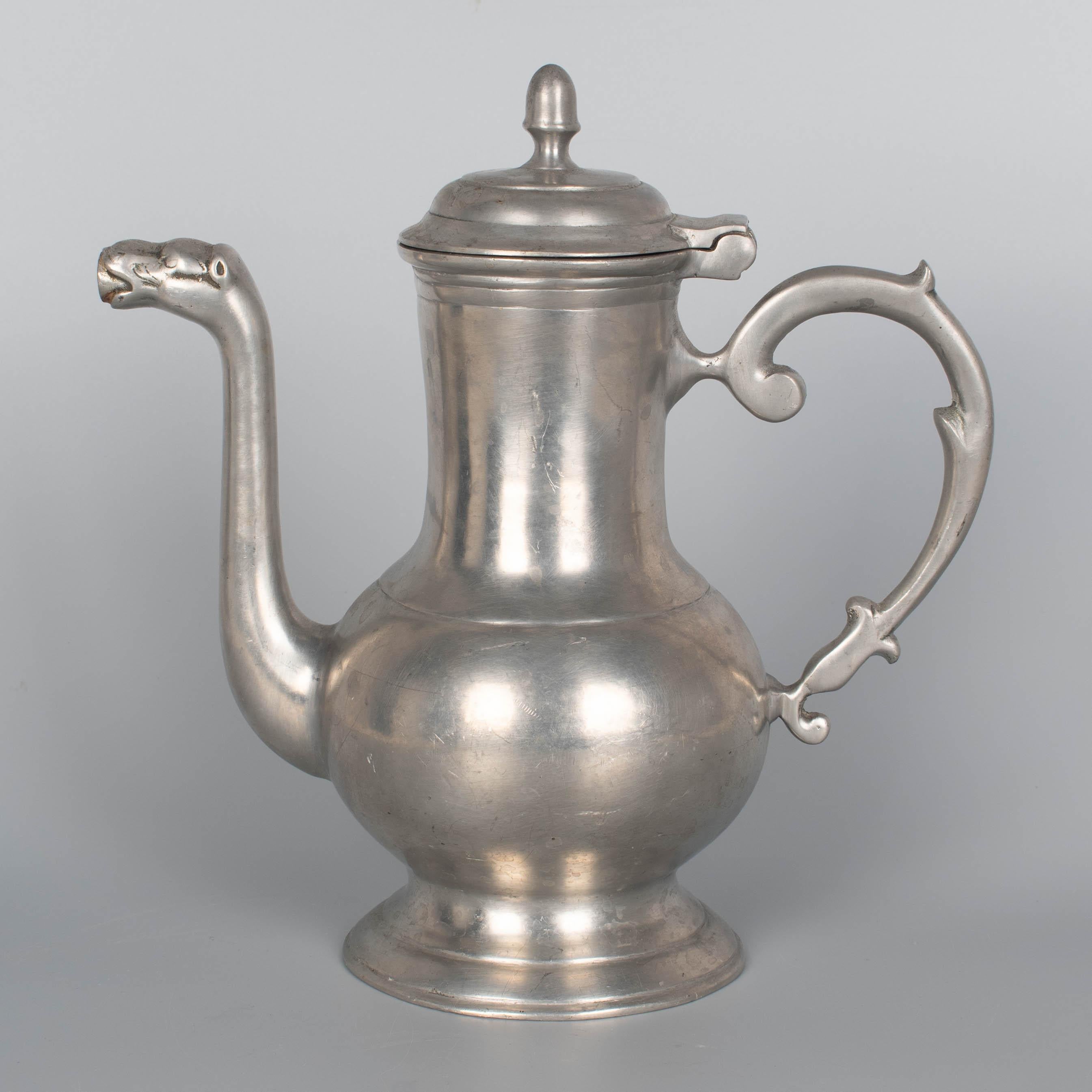 19th Century German pewter lidded coffee pot by Gustav Metten featuring an elongated body, hinged lid with acorn finial, a curved spout with dragon's head and an ornate handle. Maker's mark on bottom: G. Metten along with crown and castle marks. The