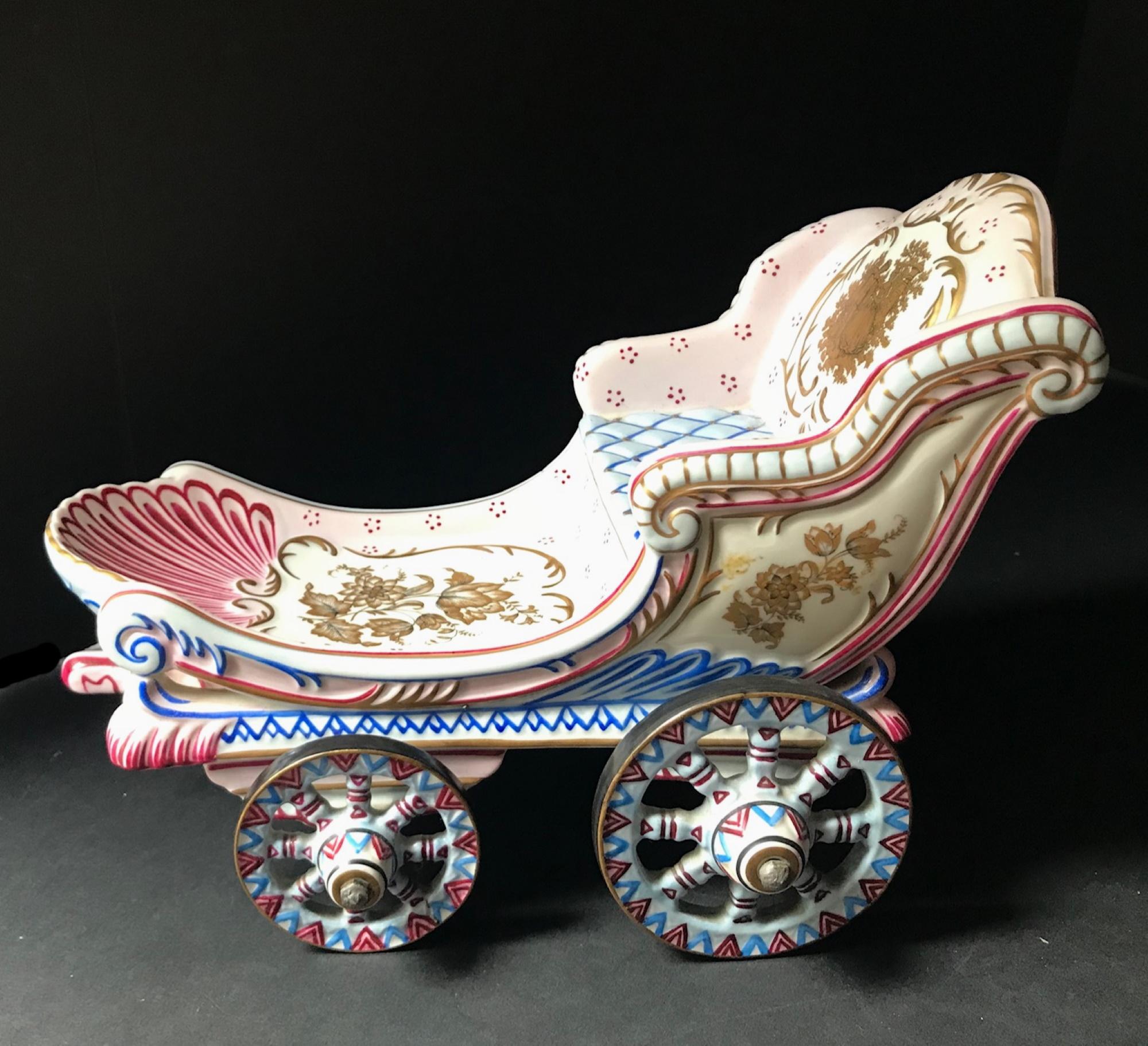 This highly decorative porcelain is pristine and functions with ease. The wheels of the cart move it back and forth securely. The rear of the carriage features the Royal Coat of Arms of the Kingdom of Liechtenstein, nestled within Switzerland. The