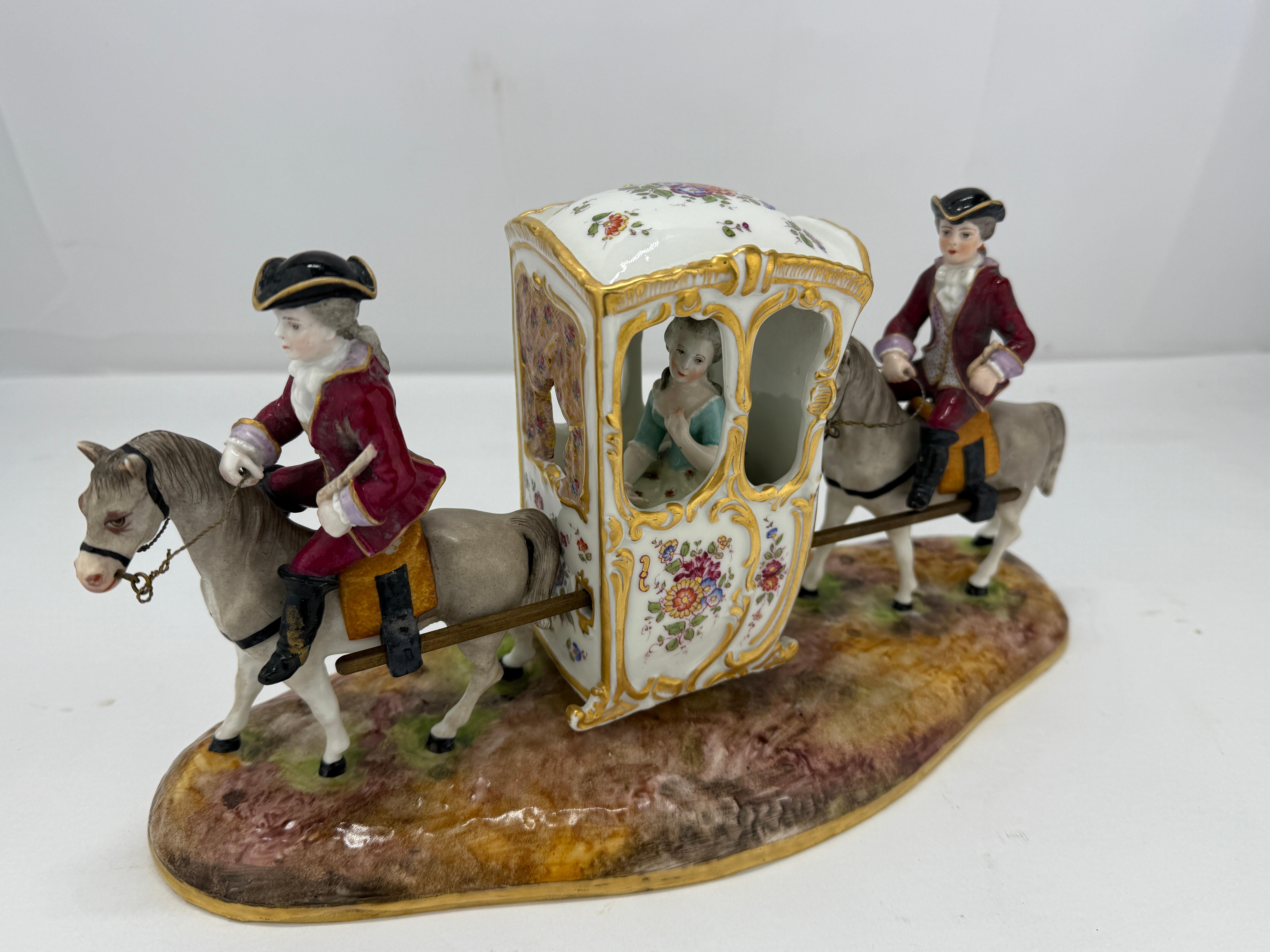 This charming 19th-century porcelain figurine group, created by Samson & Cie of Paris, captures the elegance and whimsy of 18th-century European decorative arts. The scene features an ornate carriage drawn by two finely detailed horses, each ridden