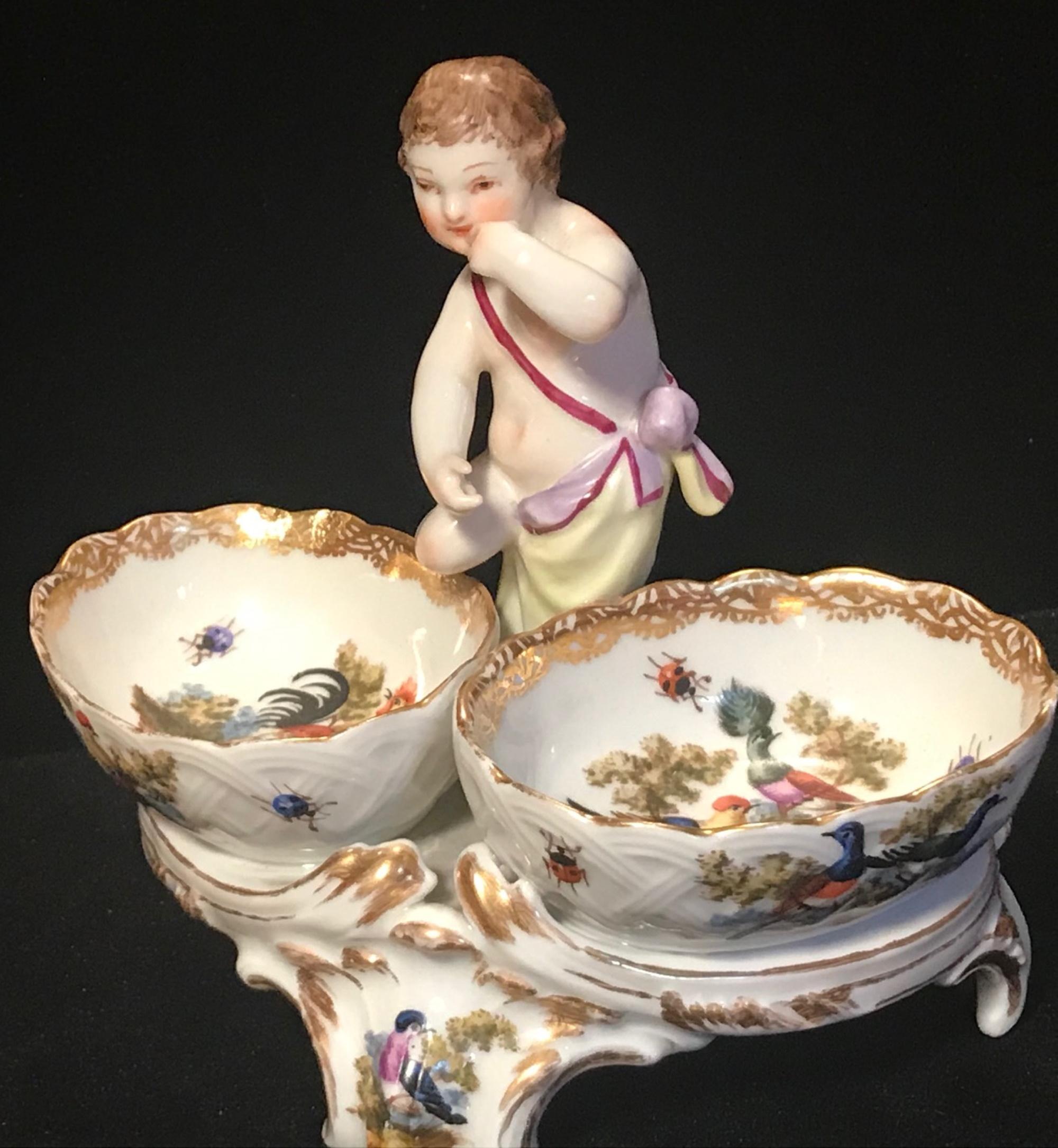 This open salt was made in the 19th century in typical Rococo style. The interior of the salt basin and the stand is delicately painted with birds, flowers and insects. In the center, on top, stands a figure of an gesticulating cherub.