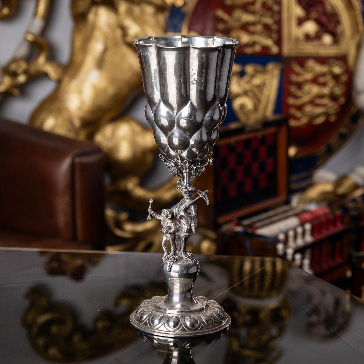Antique 19th Century German solid silver cup, made in the style of the early-17th Century examples originally made in Augsburg and Nuremberg. Standing on adorned circular foot chased with lobes, the stem shaped as an archer and his young assistant,