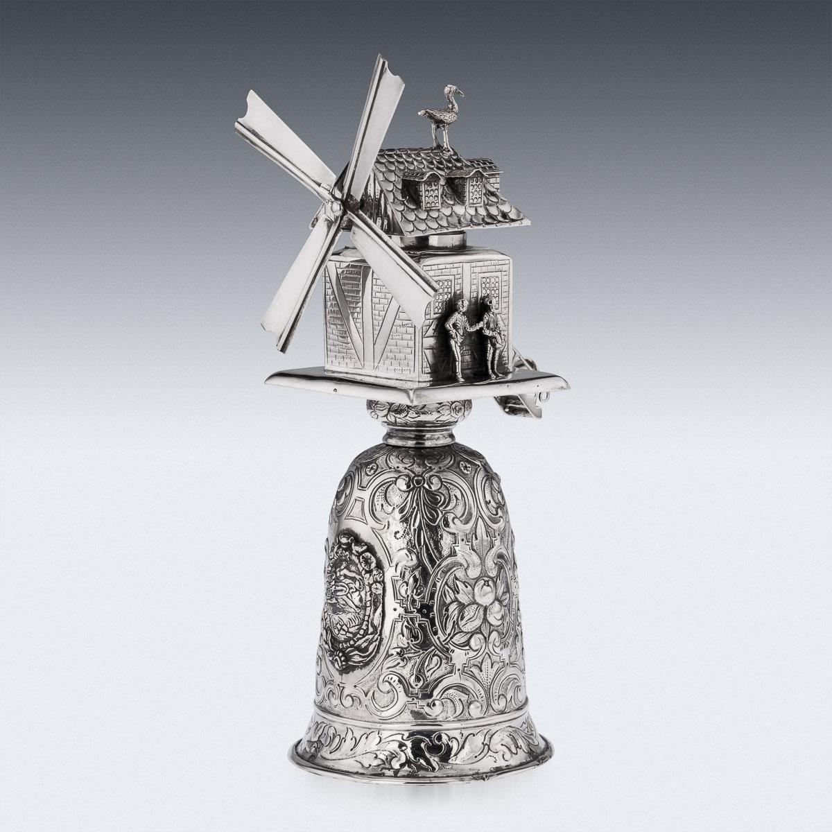 19th century German silver windmill cup, unusually large and heavy, in the style of the 17th and 18th Century example, the inverted cup chased with scrolling foliage and mythological figures, the top mounted with a working windmill (blow and the