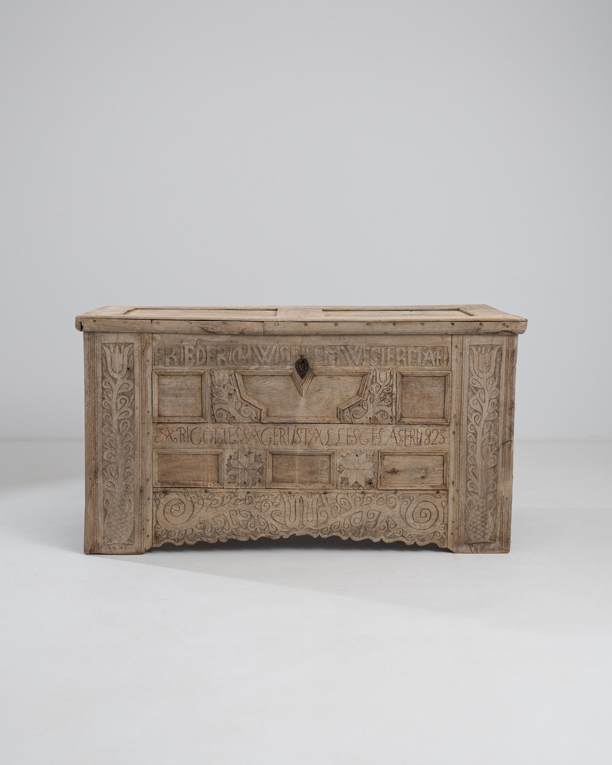 Un baule in legno proveniente dalla Germania, circa 1823. Questo enorme tronco è scrupolosamente scolpito dalla testa ai piedi con una sensibilità horror vacuii. Intagliato con il nome dell'ex proprietario, le lettere e i motivi floreali e stellari