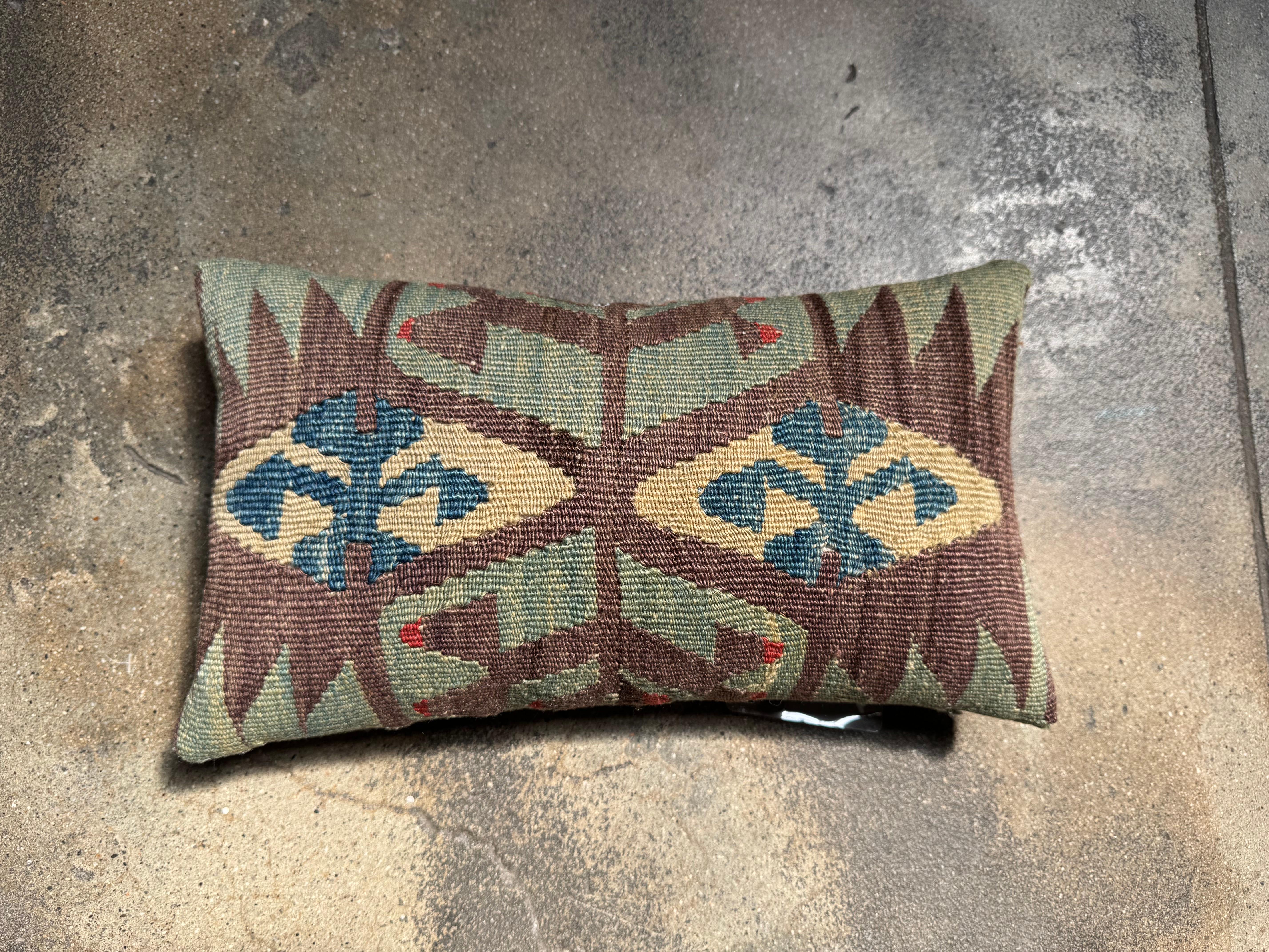 Ce coussin Kilim Ghashghai du XIXe siècle est une pièce raffinée de l'histoire du textile persan, tissé à la main par des artisans nomades avec des détails extraordinaires. Présentant des motifs symboliques dans de riches tons de terre - vert olive,