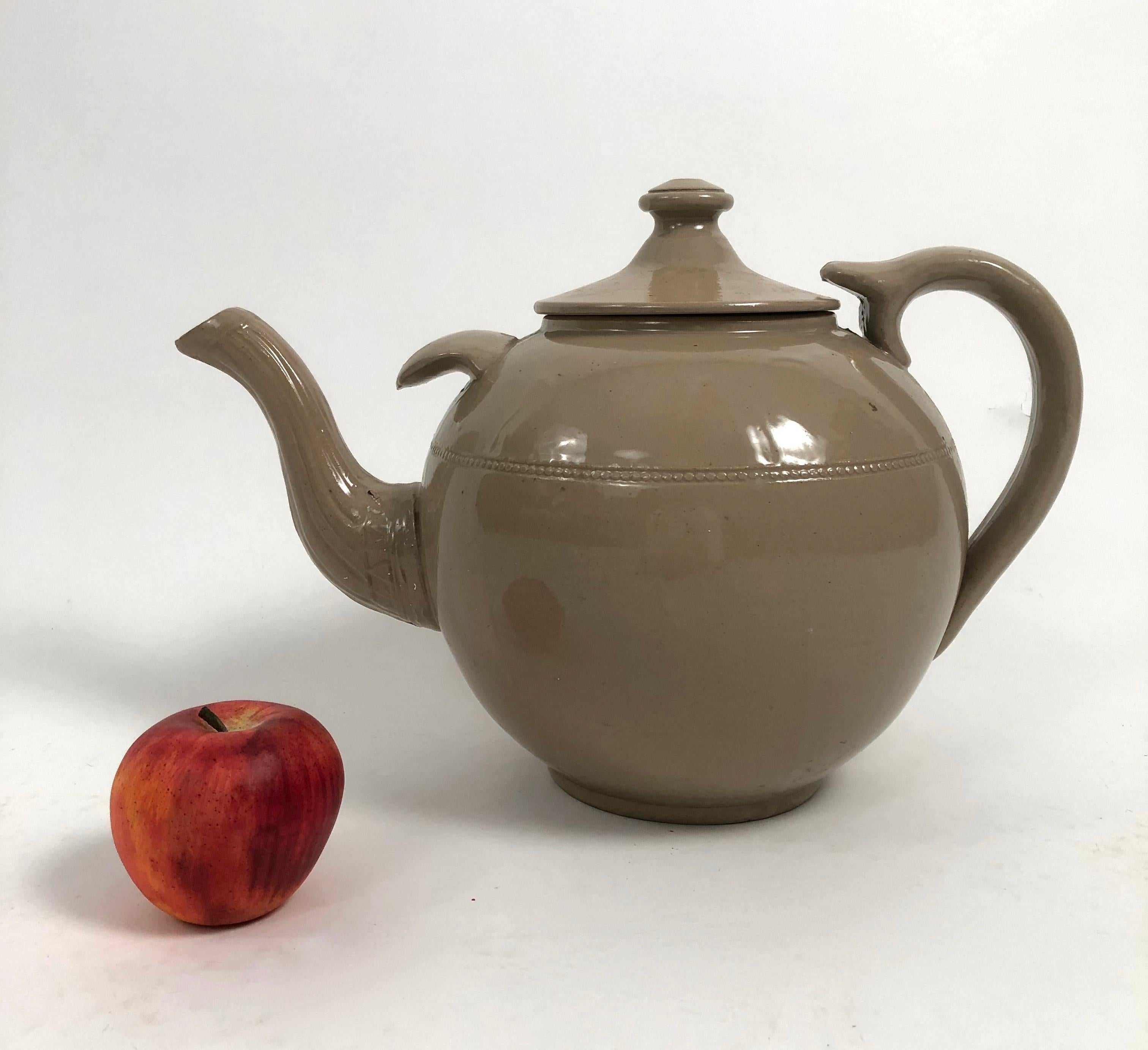 A 19th century giant English Staffordshire pottery drabware teapot of typical globular form with notch above the spout for added stability when pouring, decorated with impressed geometric decoration on the spout and with a string of pearls band