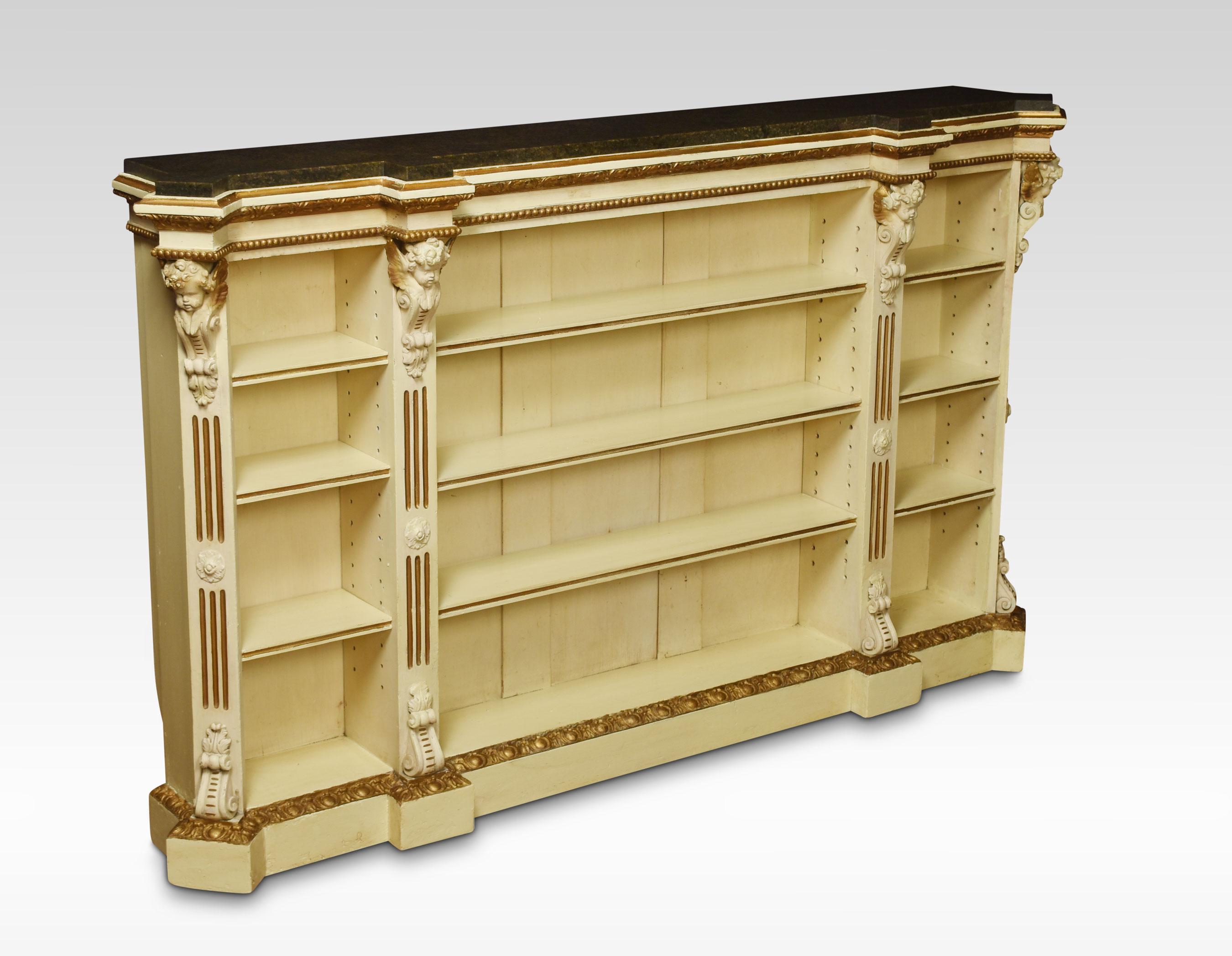 19th century gilded and painted open bookcase, the large rectangular inset marble top with canted corners applied with cherub mask brackets above gilt embellished fluted detail enclosing three bays of adjustable shelving. All raised up on a plinth