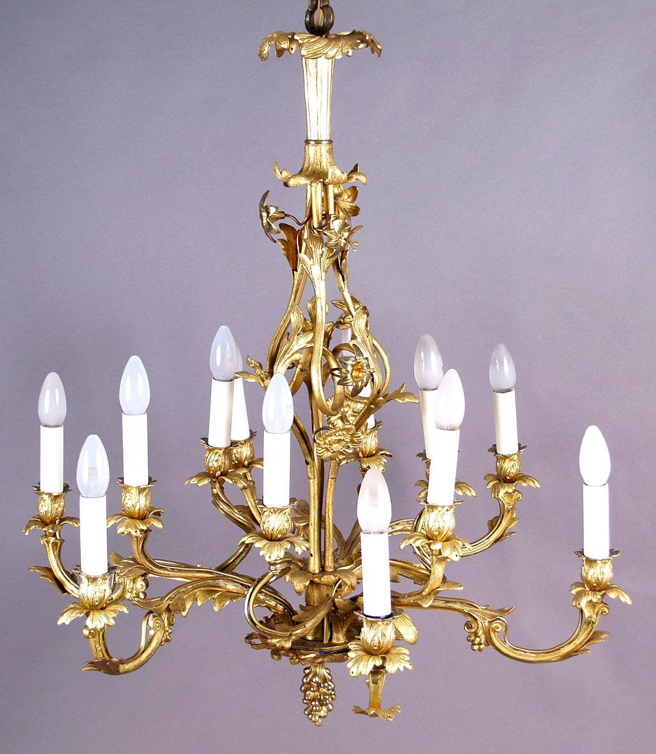 19th century gilded bronze 12-arm candle chandelier
A candle chandelier with twelve arms placed on four large arms attached to the stem. Each of the arms of the chandelier is slender, profiled in the form of plant twigs and twigs, curled upwards.