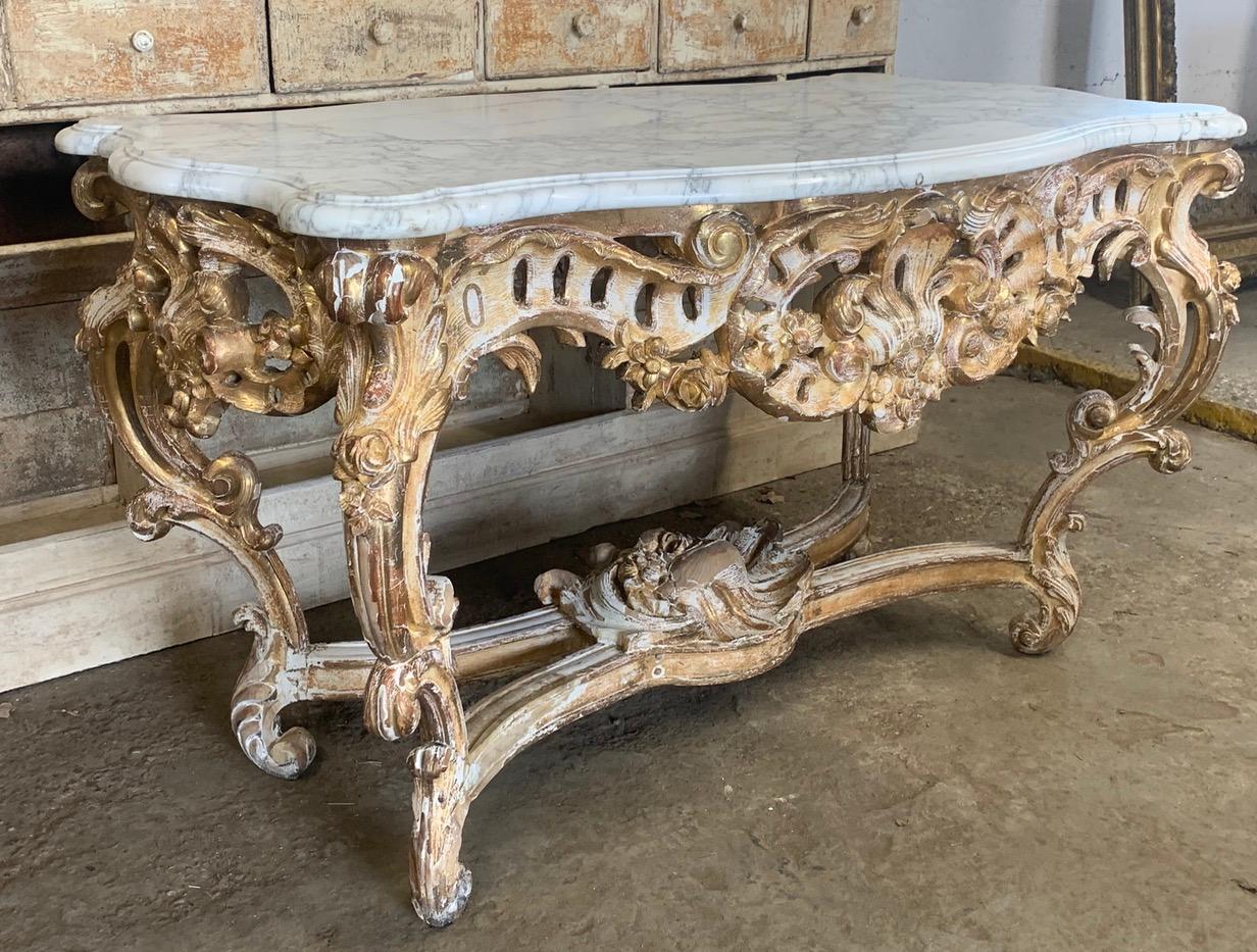 A stunning 19th Century gilded carved wood Rococo center table with a Carrara marble top. The base has carved decoration on all 4 sides with lovely wear to the original gilding giving it a great look.