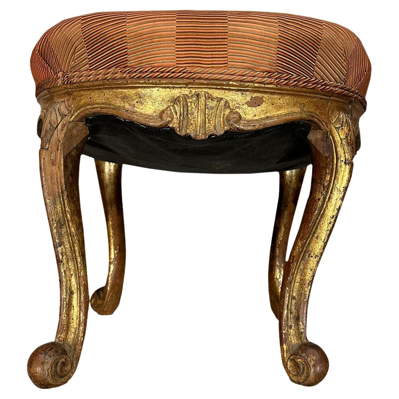 A 19th century, Italian Venetian stool, gilded throughout with a lot of patina the fabric is silk. The bench is all hand carved and the legs go into a swirl at the bottom.