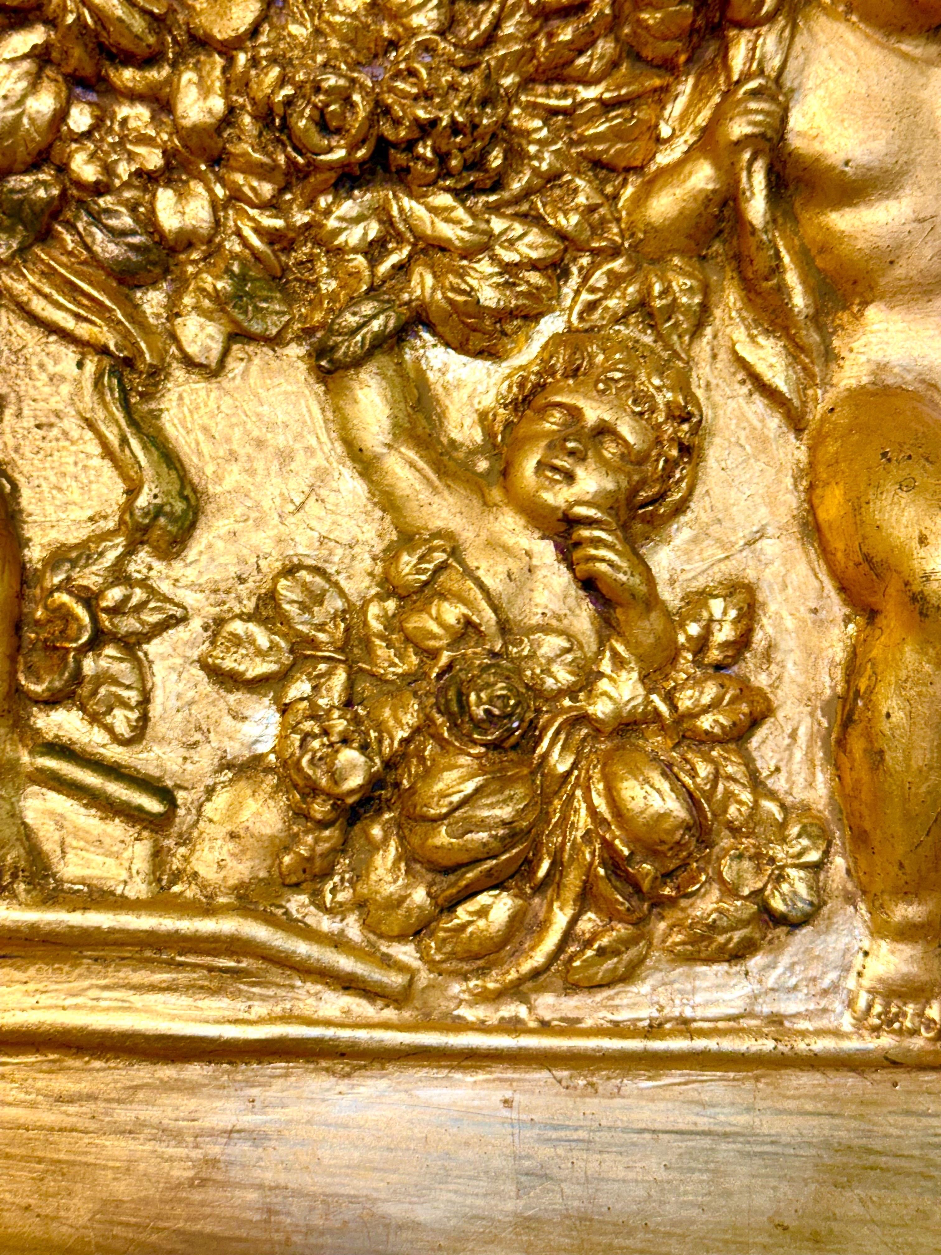 Ce bas-relief ovale raffiné en plâtre doré est un exemple remarquable de l'art décoratif du XIXe siècle dans la tradition néoclassique. La composition représente une scène animée de putti, ou chérubins, enjoués, entourés d'abondantes guirlandes
