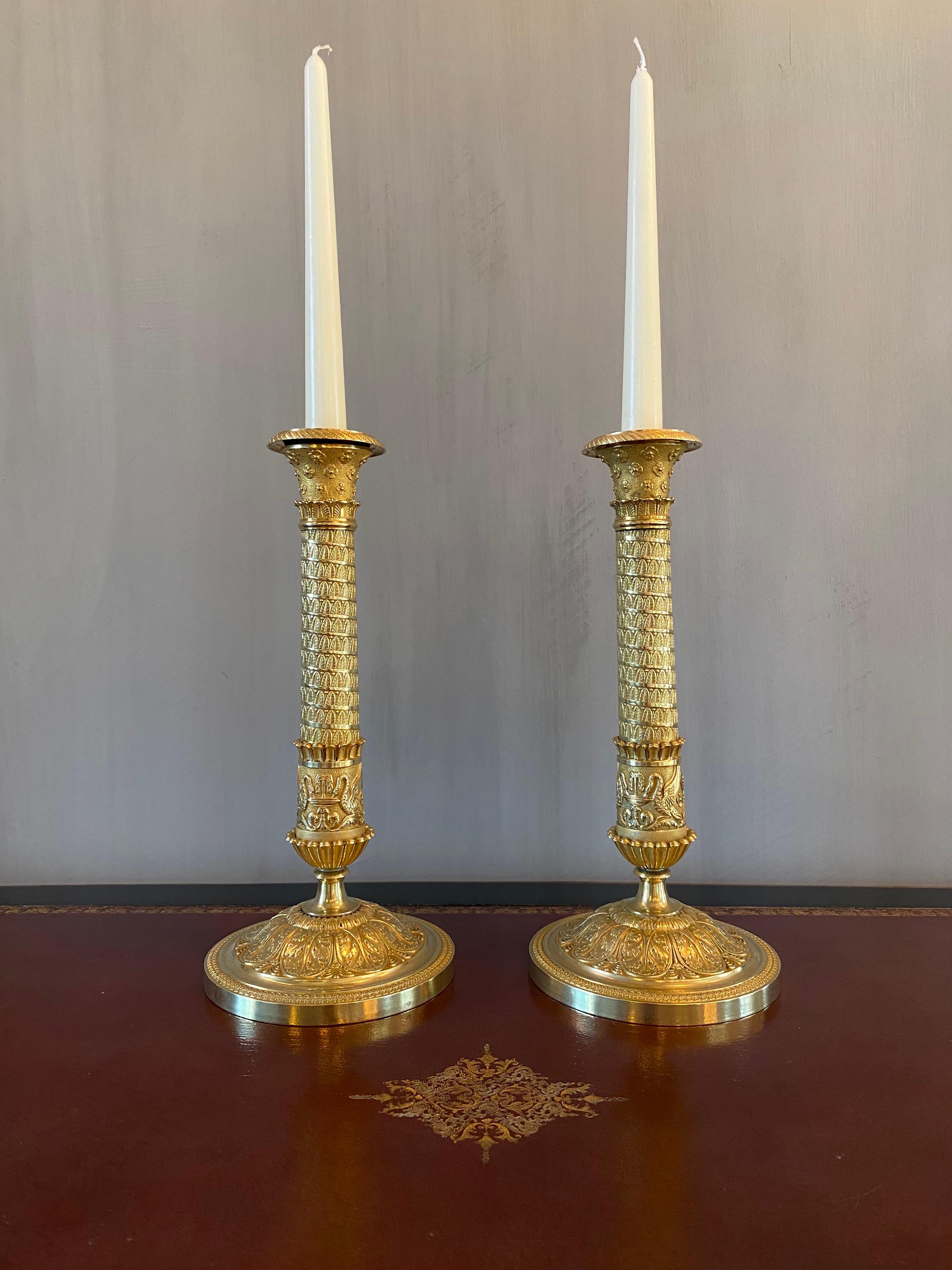 A fabulous and elegant large pair French candlesticks in gilt and chased bronze.
The central shafts in style of Trajan's column or the column of the place Vendôme in Paris, is decorated with frieze of palmettes and swans drinking in fountains ending