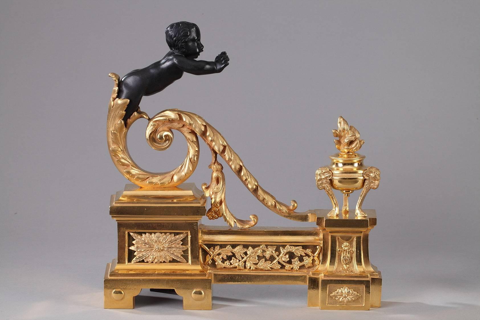Gilt and patinated bronze andirons à enfants arabesques. Each andiron is decorated with a patinated putto bursting out of gilded, arabesque acanthus leaves, stretching his hands out to warm them in the fire. A burning Athenienne, or tripod incense