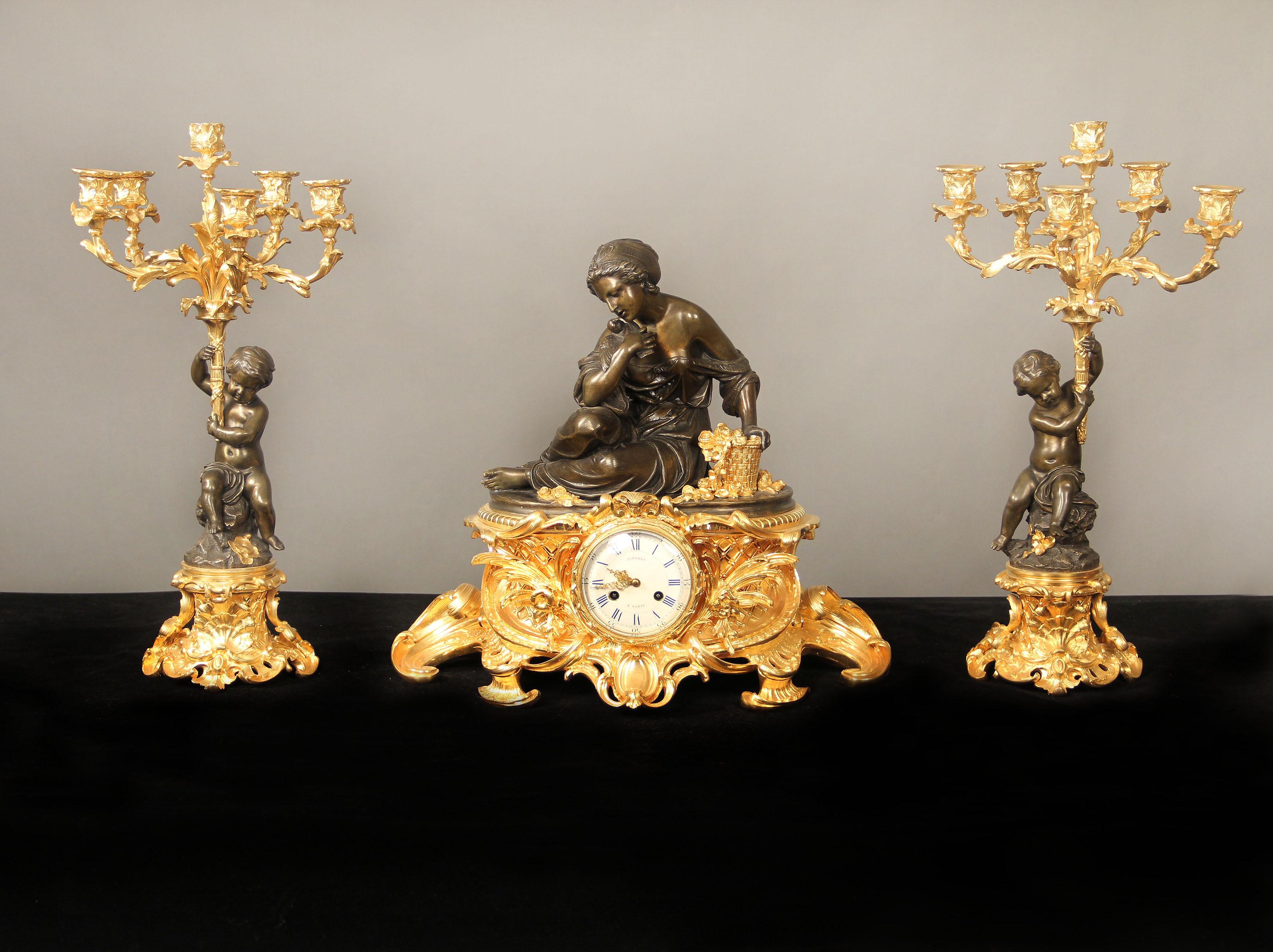 Ein feines dreiteiliges Uhrenset aus vergoldeter und patinierter Bronze aus der Mitte des 19

Von Victor Pierret

Die figurale Uhr mit einer Frau und einem Vogel, die neben einem Rosenkorb sitzen, steht auf einem vergoldeten Sockel, der mit