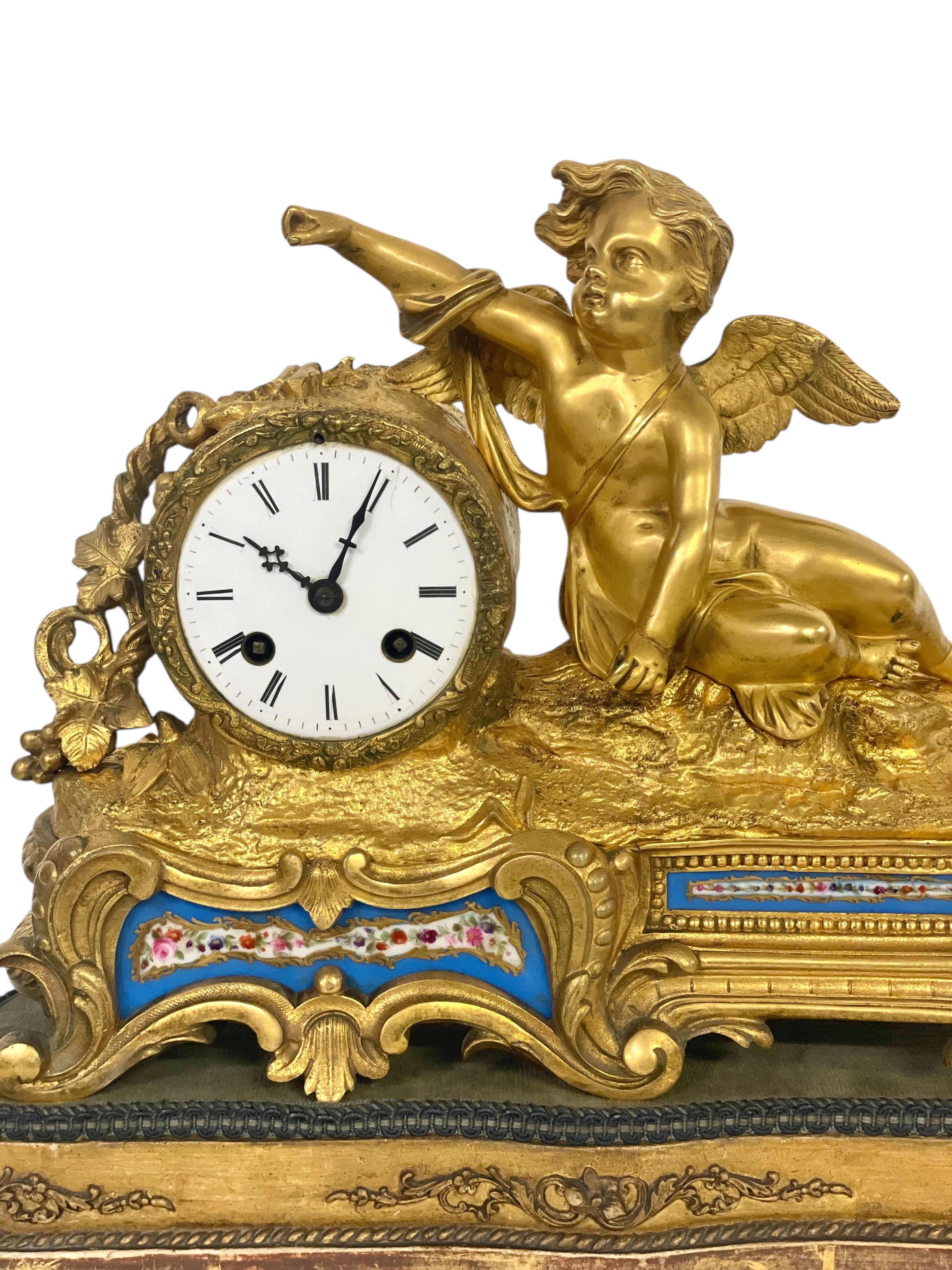 This exquisite 19th-century gilt bronze and porcelain clock is a stunning example of French decorative arts. The clock features a charming cherub figure, complete with expressive face and intricately sculpted wings, holding an arrow. The white