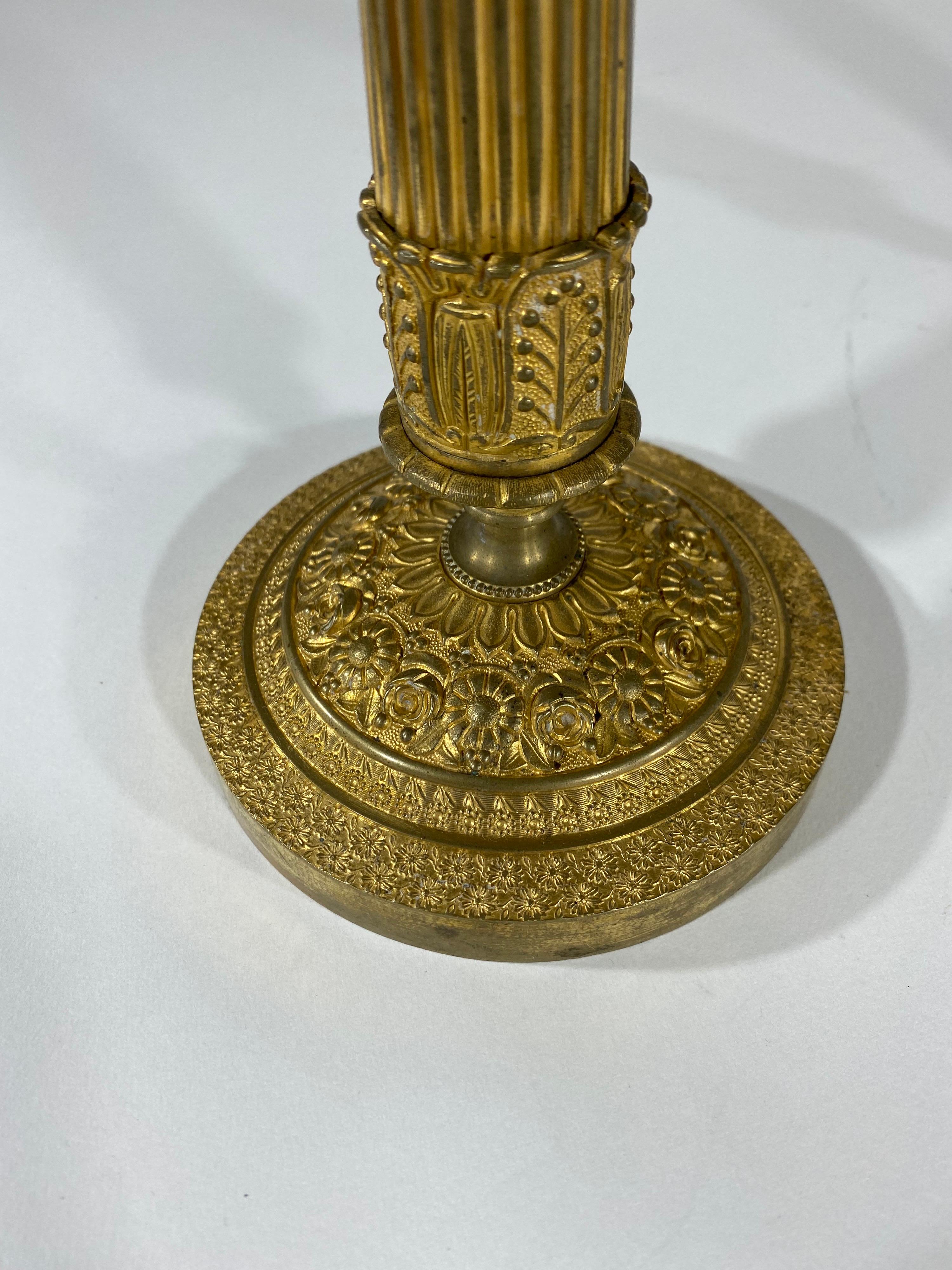 Pair French gilt bronze table sticks with classical decoration. unusual floral and fruit baskets on top of columnar supports. Floral ground at base with fluted columns and engine turning around both base and top bobeche.