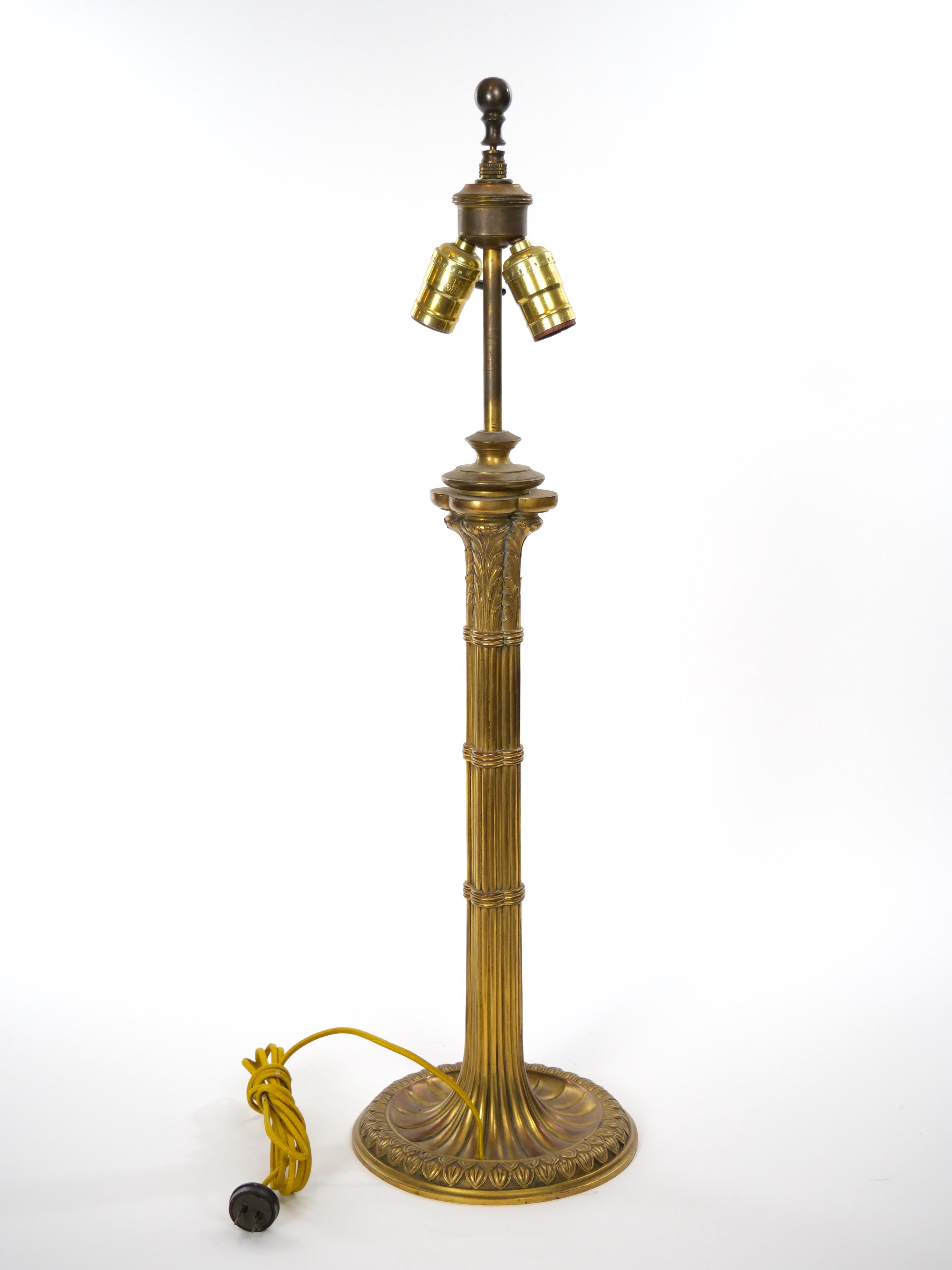 Mid 19th century gilt bronze candlestick style table lamp resting on a round pedestal base with silk fringe shade. The lamp is in great working condition. Minor wear consistent with age / use. Shade is worn with small tear.