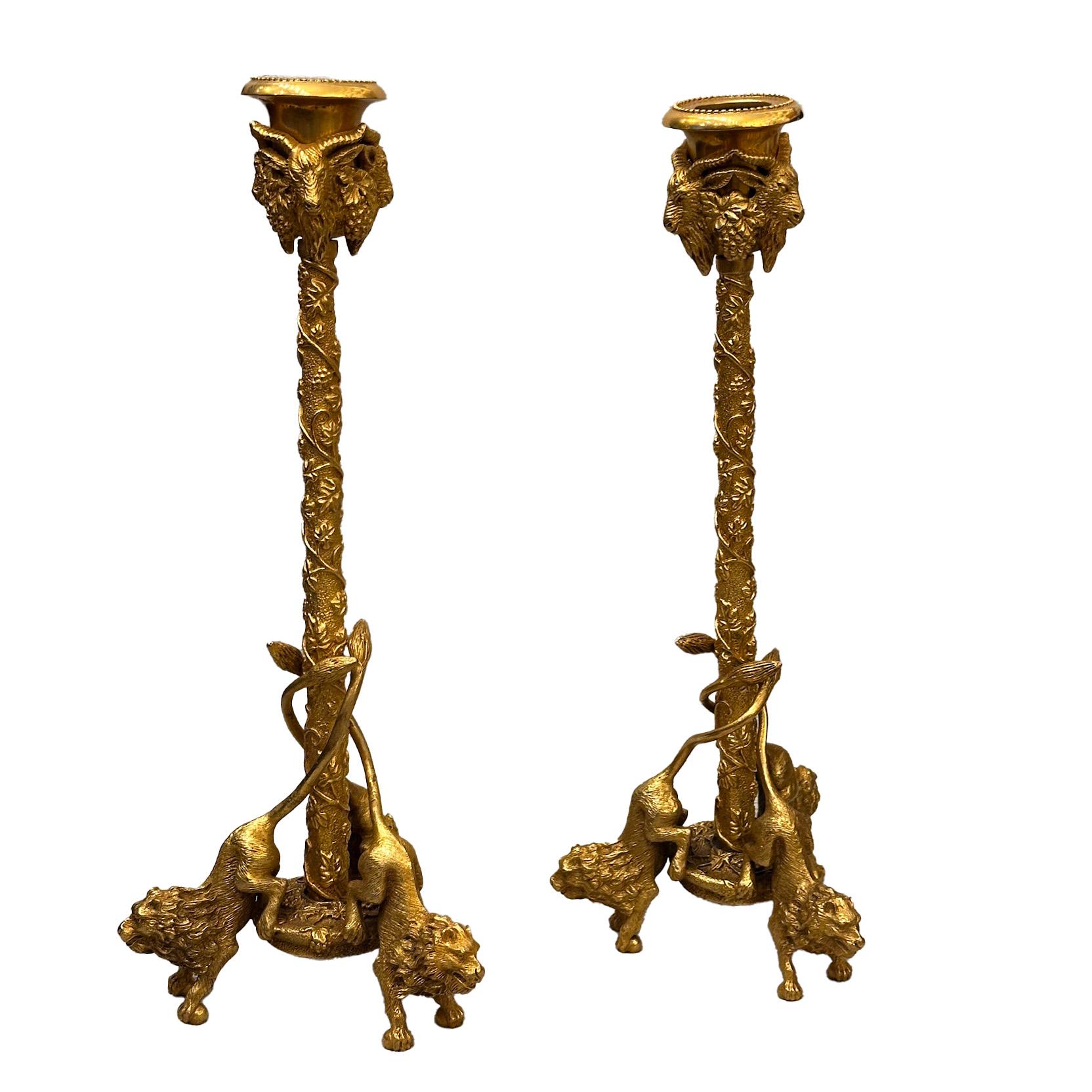 Ecco una splendida coppia di candelabri in bronzo dorato finemente cesellato della metà del XIX secolo. Ogni candeliere presenta teste di ariete e grappoli d'uva sulla base, mentre il fusto è ornato da motivi a foglie e viti. La base è sostenuta da
