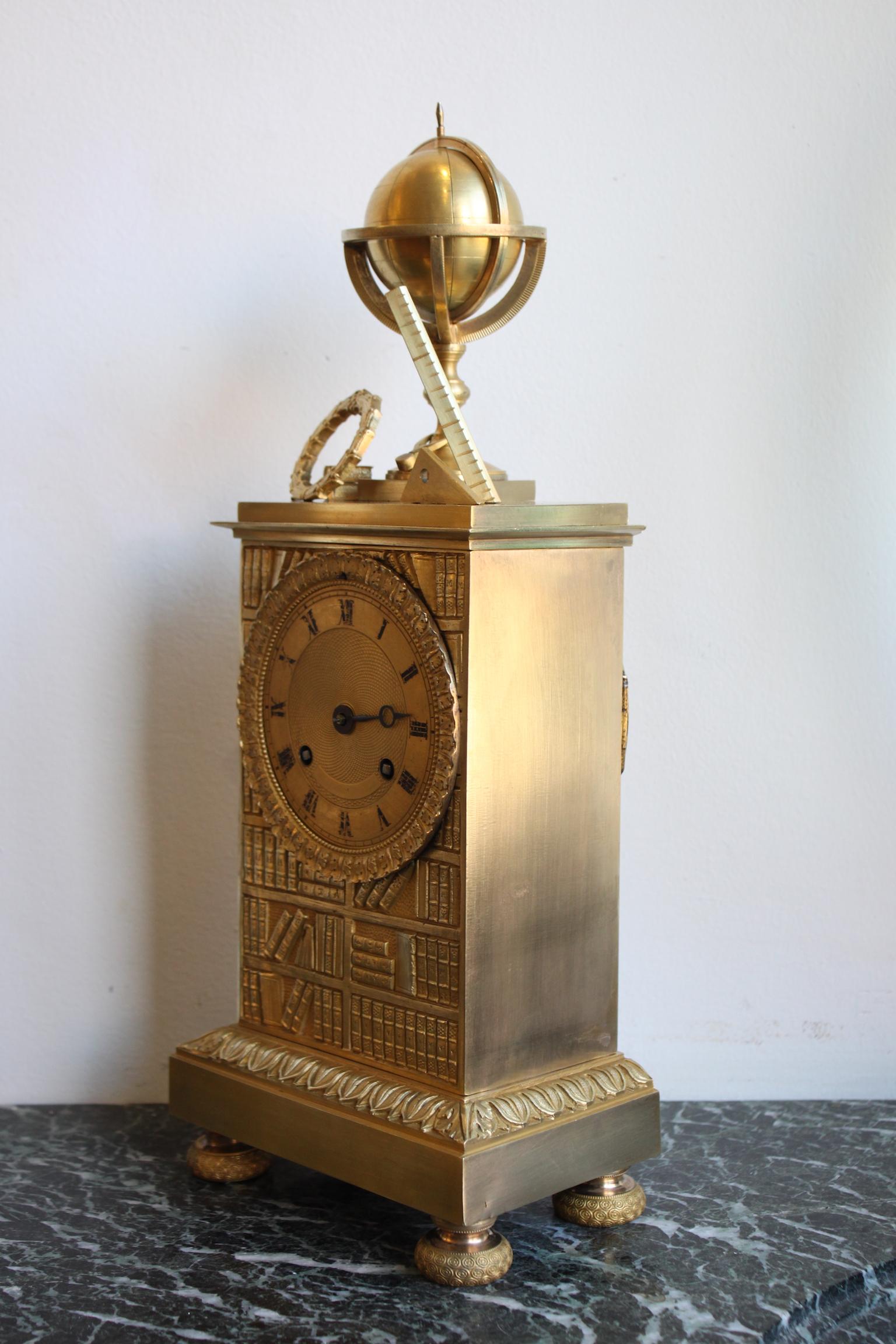 19th century gilt bronze clock representing an Allegory of Science, surmounted by a globe, books, scientific instruments and a laurel wreath.
Dimensions: Width 15cm, height 37.5cm, depth 9.5cm 
In working order.