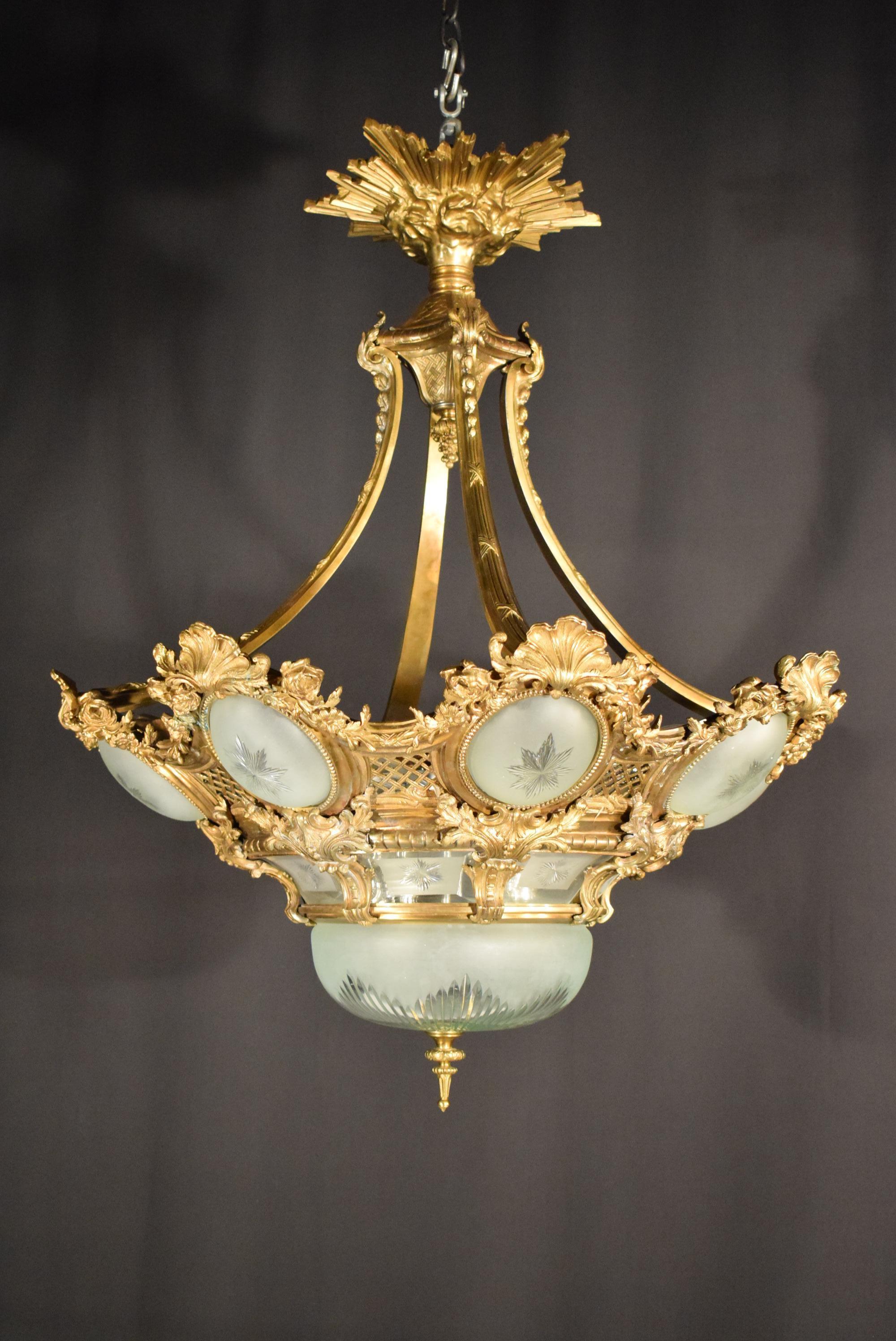 A very fine gilt bronze and crystal chandelier in the Regence style. The top depicting sun rays and clouds resting on a box that issues four arms that hold the body of the chandelier. The body of the chandelier features eight circular reserves (with