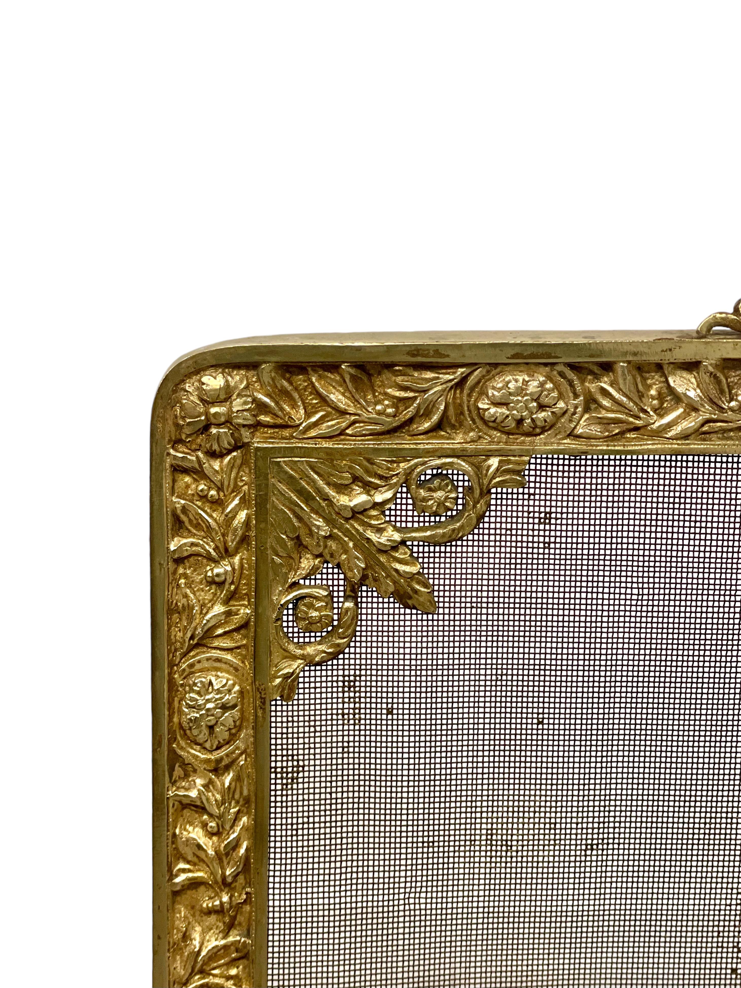 An elegant antique gilt bronze and mesh Louis XVI style fire guard, profusely decorated all round its square frame with ornate floral and foliage designs. The facade is formed from mesh wire, with a charming musically themed bronze centrepiece