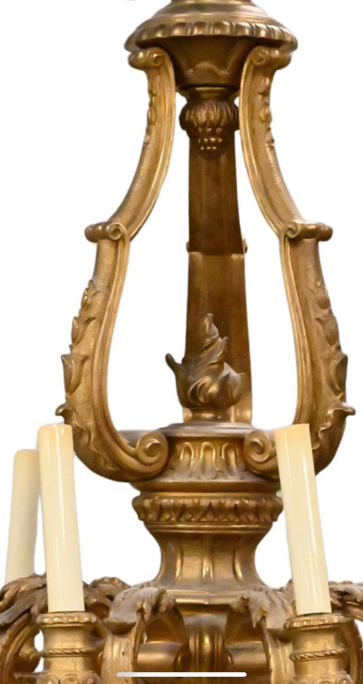 This magnificent Louis XVI-style chandelier is a testament to timeless elegance and superior craftsmanship. Made of richly patinated bronze, it features eight gracefully curved arms, each adorned with classical acanthus leaf motifs and terminating