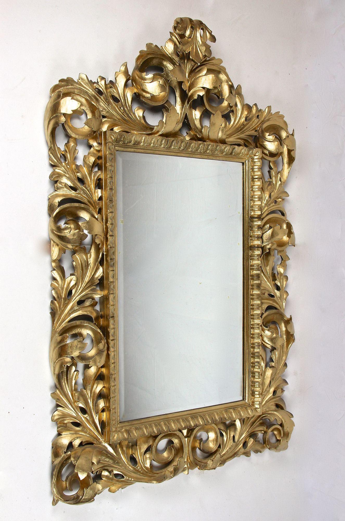 Eye-catching gilt florentine wall mirror out of Italy dating back to the end of the 19th century around 1890. The large, outstanding looking, open worked frame is ornamented by elaborately handcarved acanthus leaf motifs, confering the piece a sense