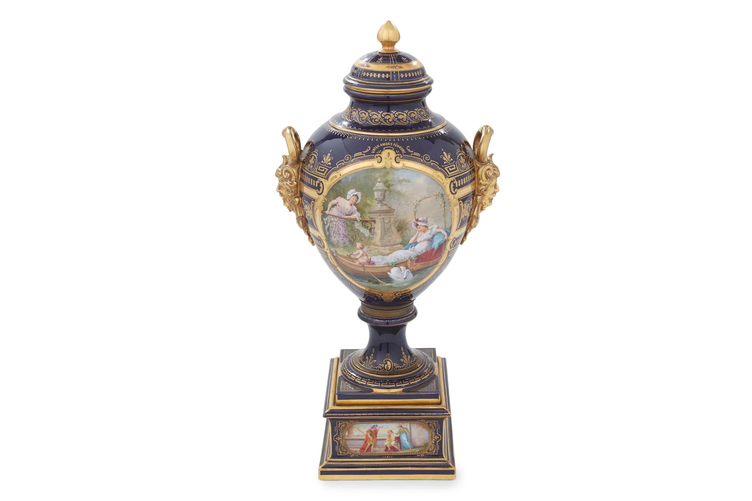 19th century gilt gold with exterior hand painted scene design details covered decorative urn / piece. The exterior garden scene details was painted by W. Schnider. The covered urn feature a baluster form, with two handles formed from a man's head.