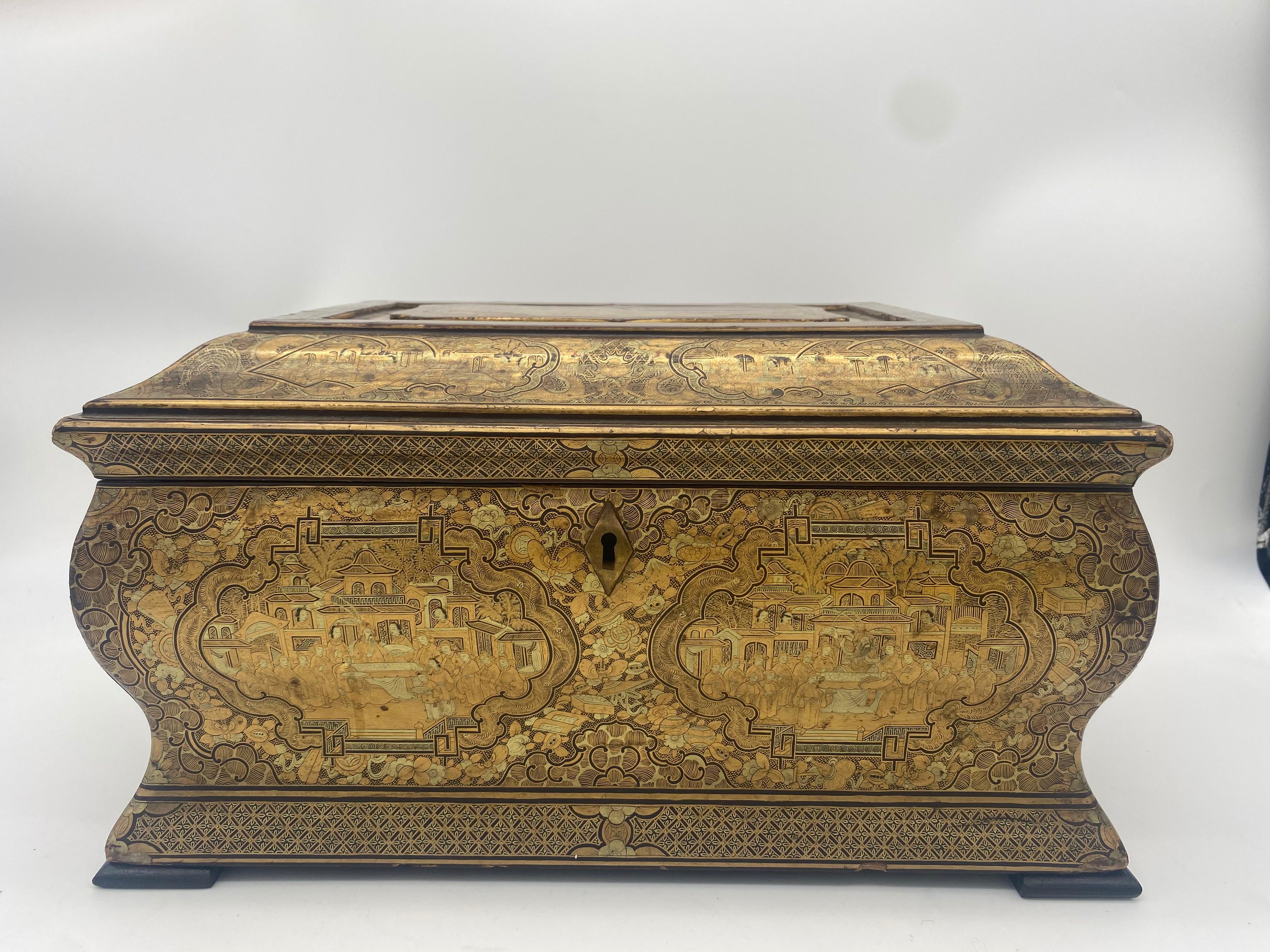 18th or 19th century lift-lid gilt-decorated goldenblack lacquer Chinese tea caddy, the rectangular-section body on a waisted foot and the hinged cover painted with shaped cartouches of figures and architecture on a busy ground of blossoms, foliage