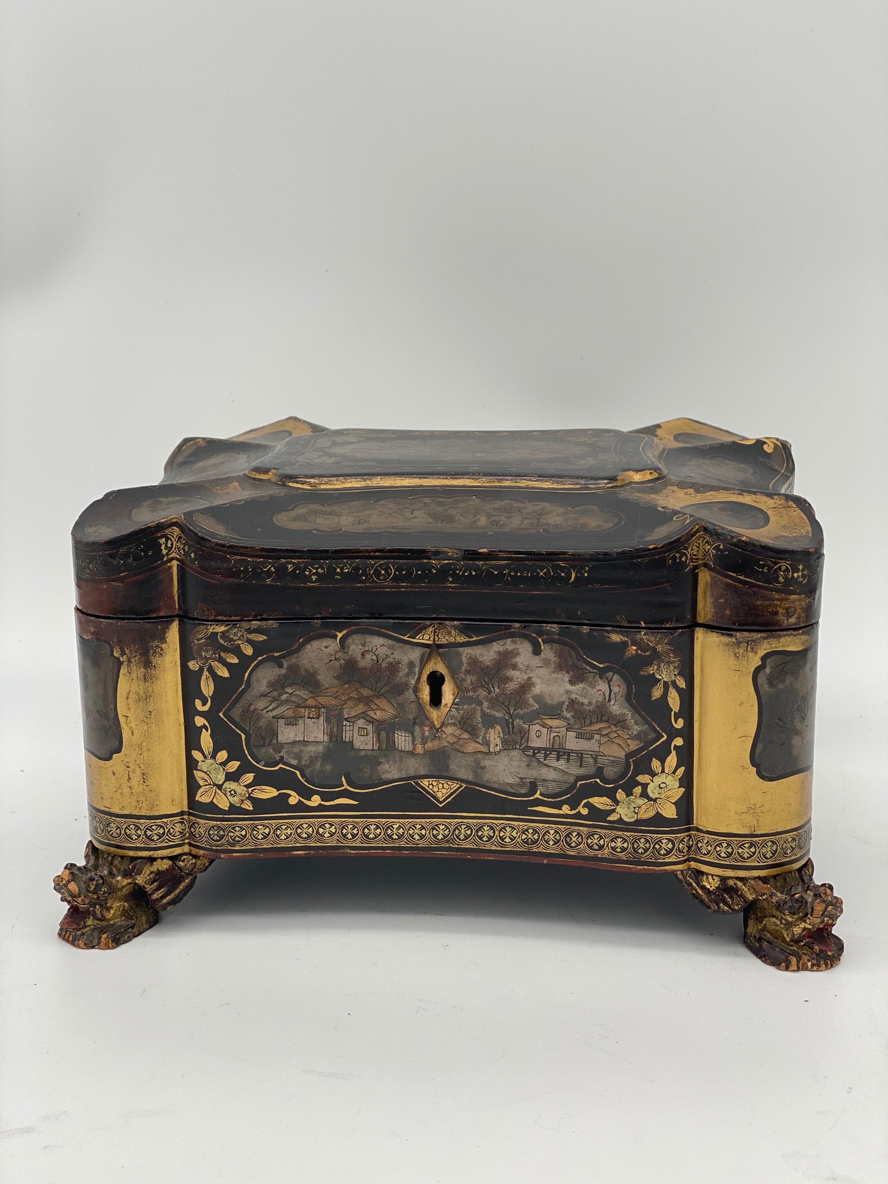 19th century golden black lacquer Chinese tea caddy with a key, the rectangular-section body decorated with panels of landscapes and patterned decoration throughout retains original hardware and is set upon carved foo lion feet, very beautiful